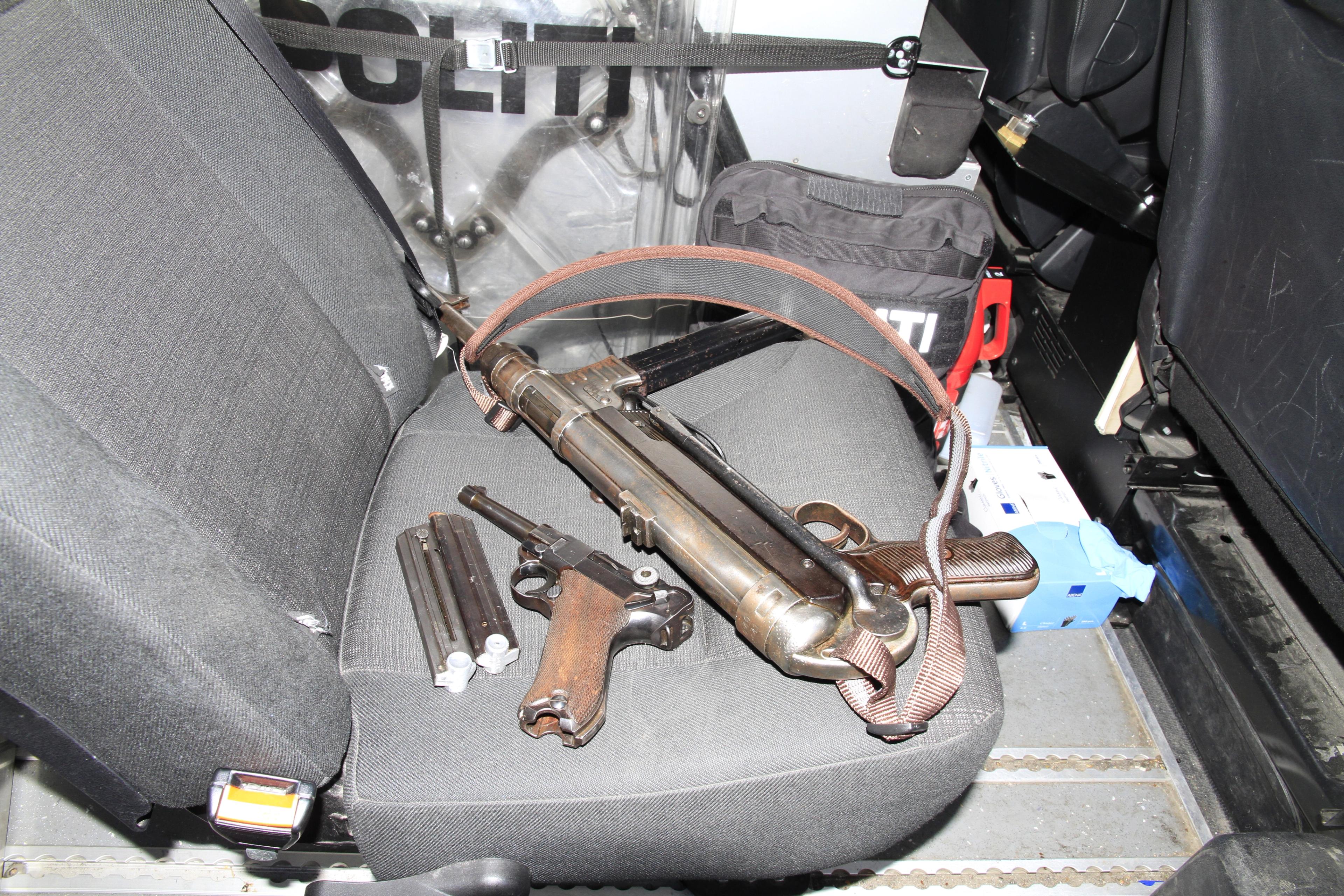 To våpen med magasiner ligger i baksetet på en politibil. Man ser beskyttelsesutstyr i bakgrunnen.