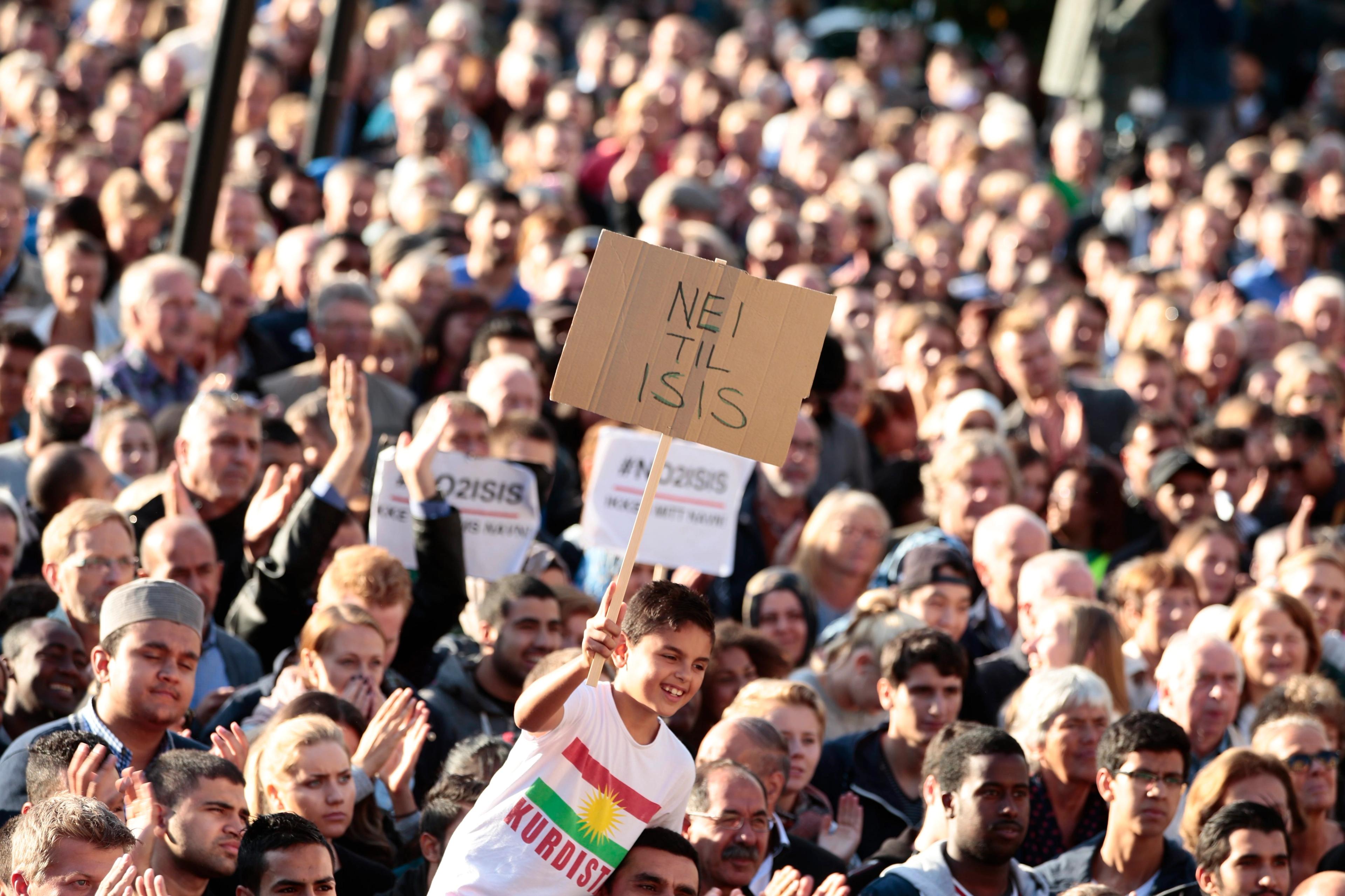 Folk samlet i demonstrasjonstog. En gutt sitter på skuldrene til noen med «Nei til ISIS»-plakat og Kurdistand-t-skjorte.