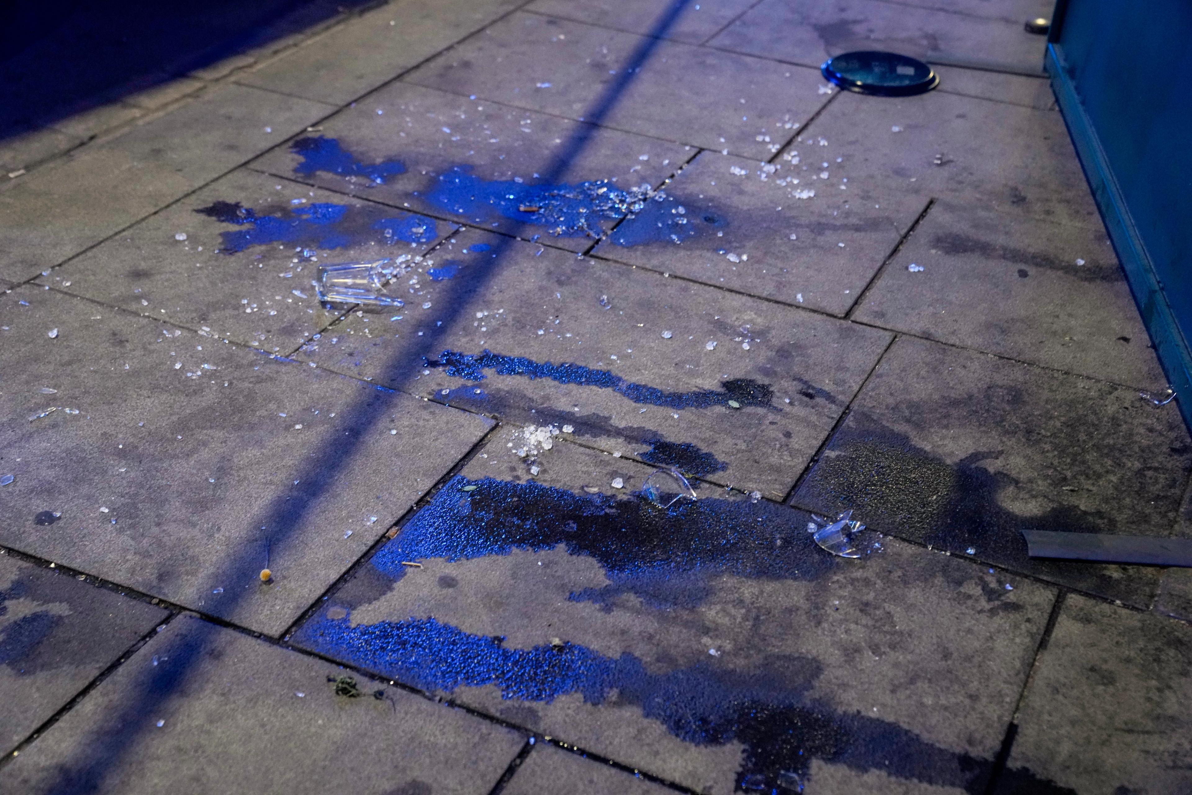 Blodflekker og knust glass ligger på fortauet.