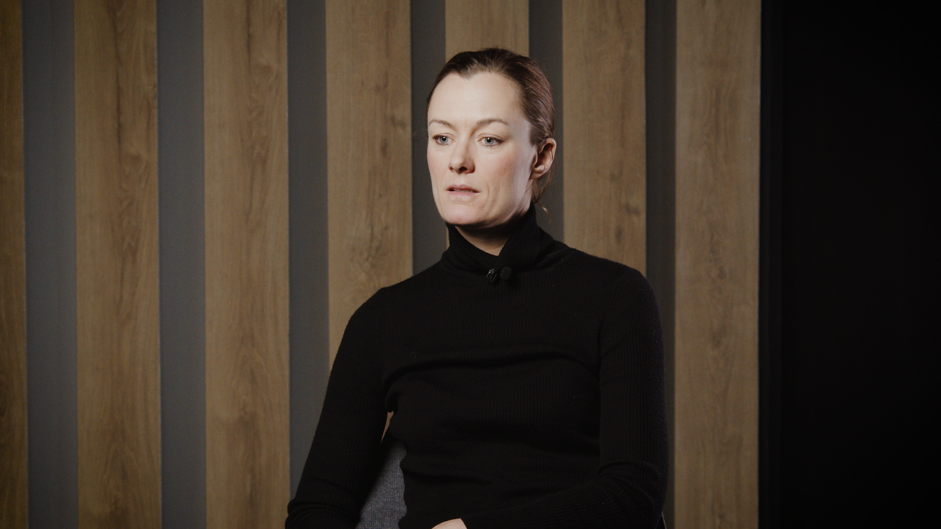 Anette Trettebergstuen sitter og forteller. Hun har svart genser og håret bakover.