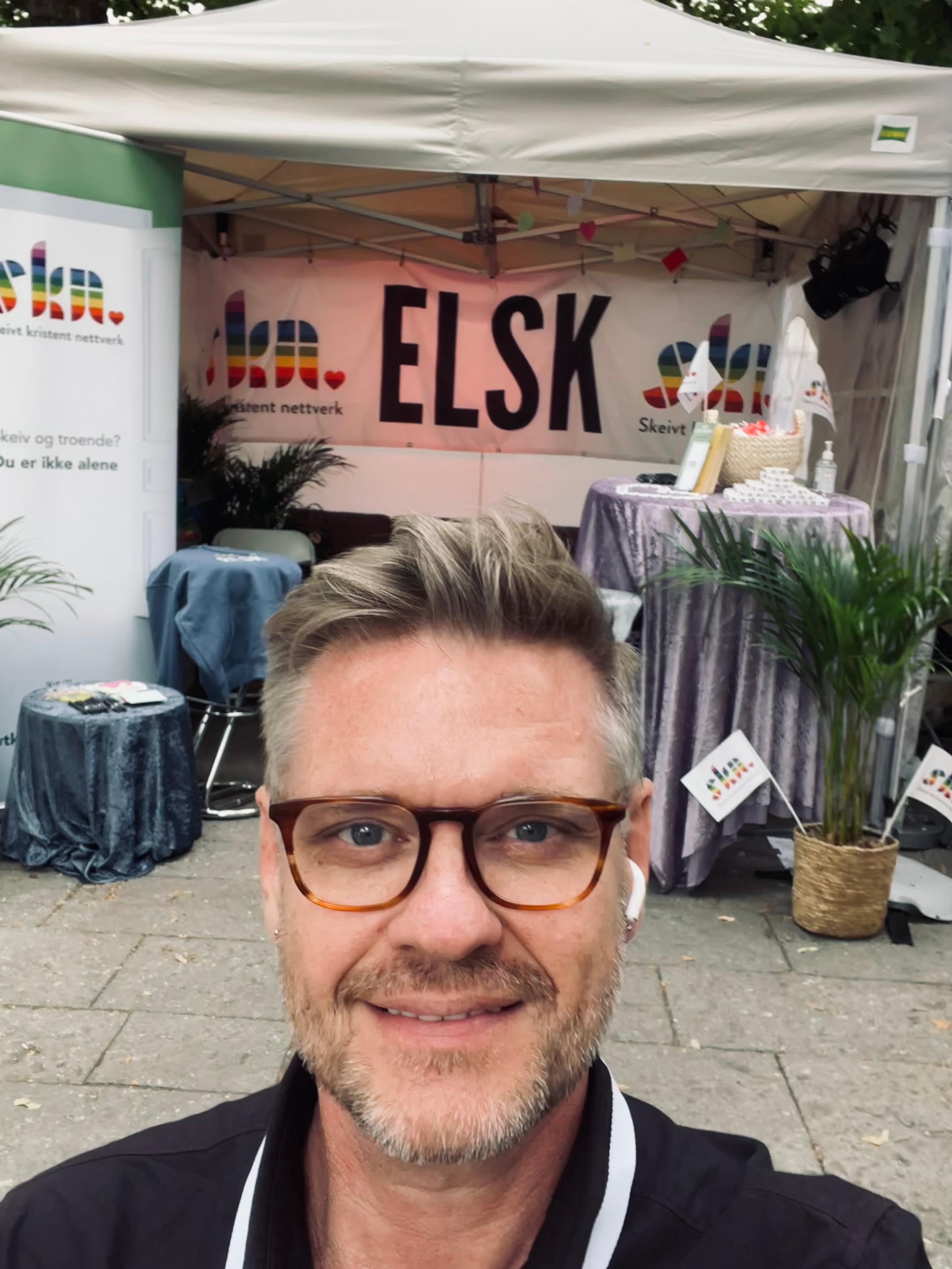 En mann foran Skeivt kristent nettverk sin stand i Pride Park.