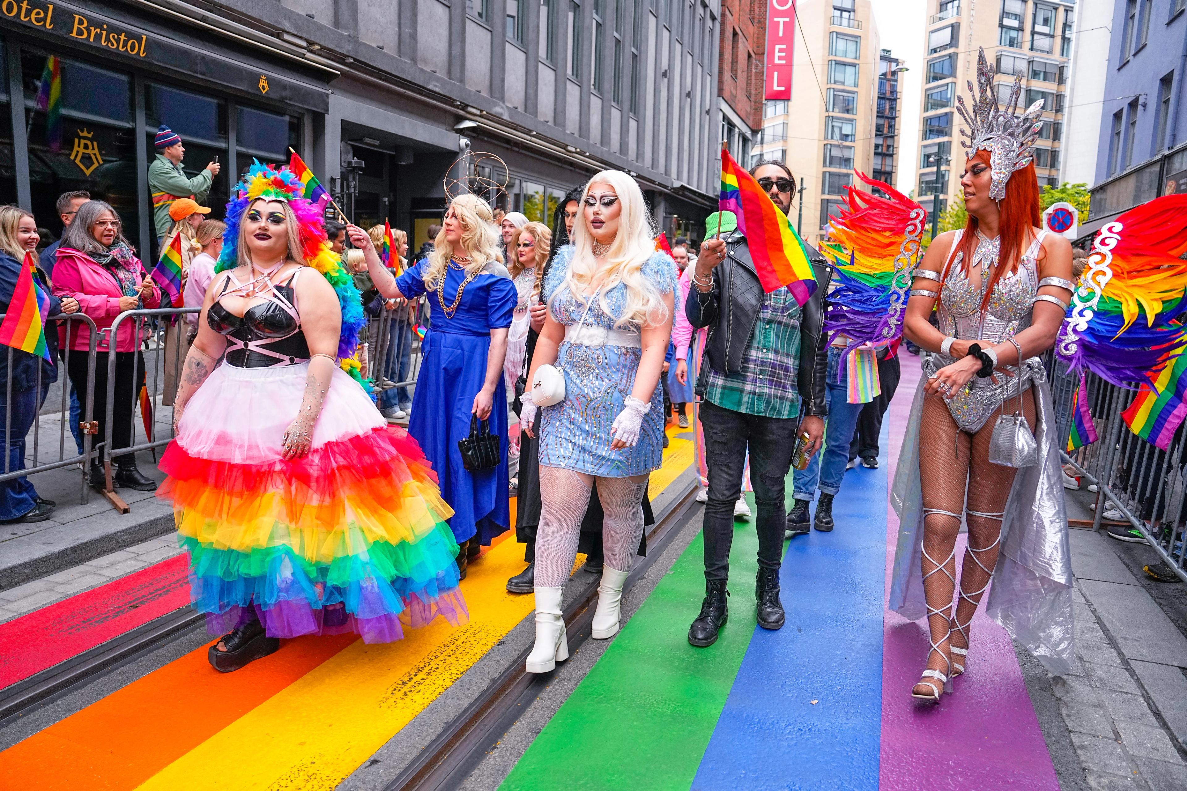 Drag queens i regnbuetoget med pride-flagg. De går nedover Rosenkrantz' gate som er malt med regnbuestriper.