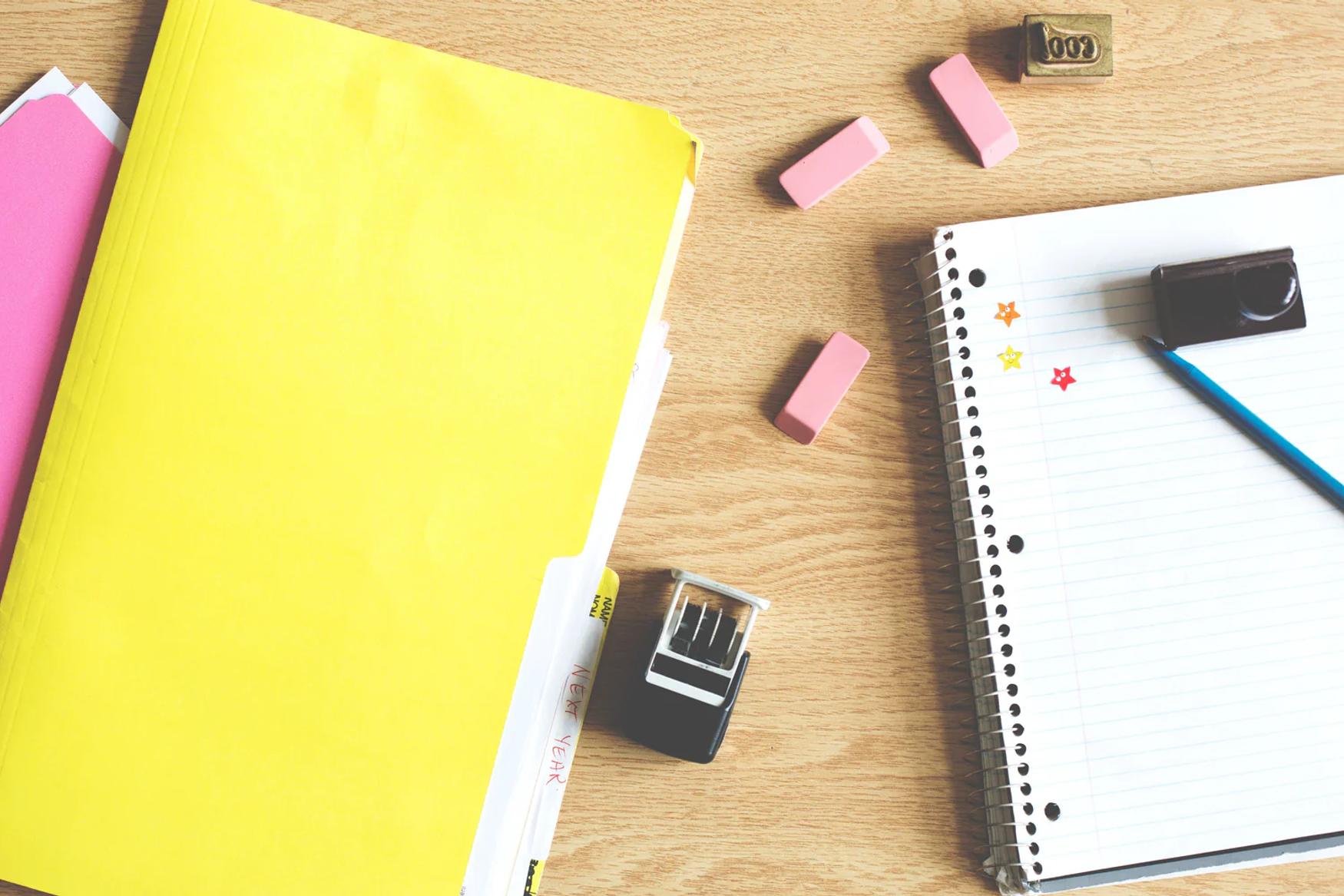 Et skrivebord med notatbøker, penner og viskelær.