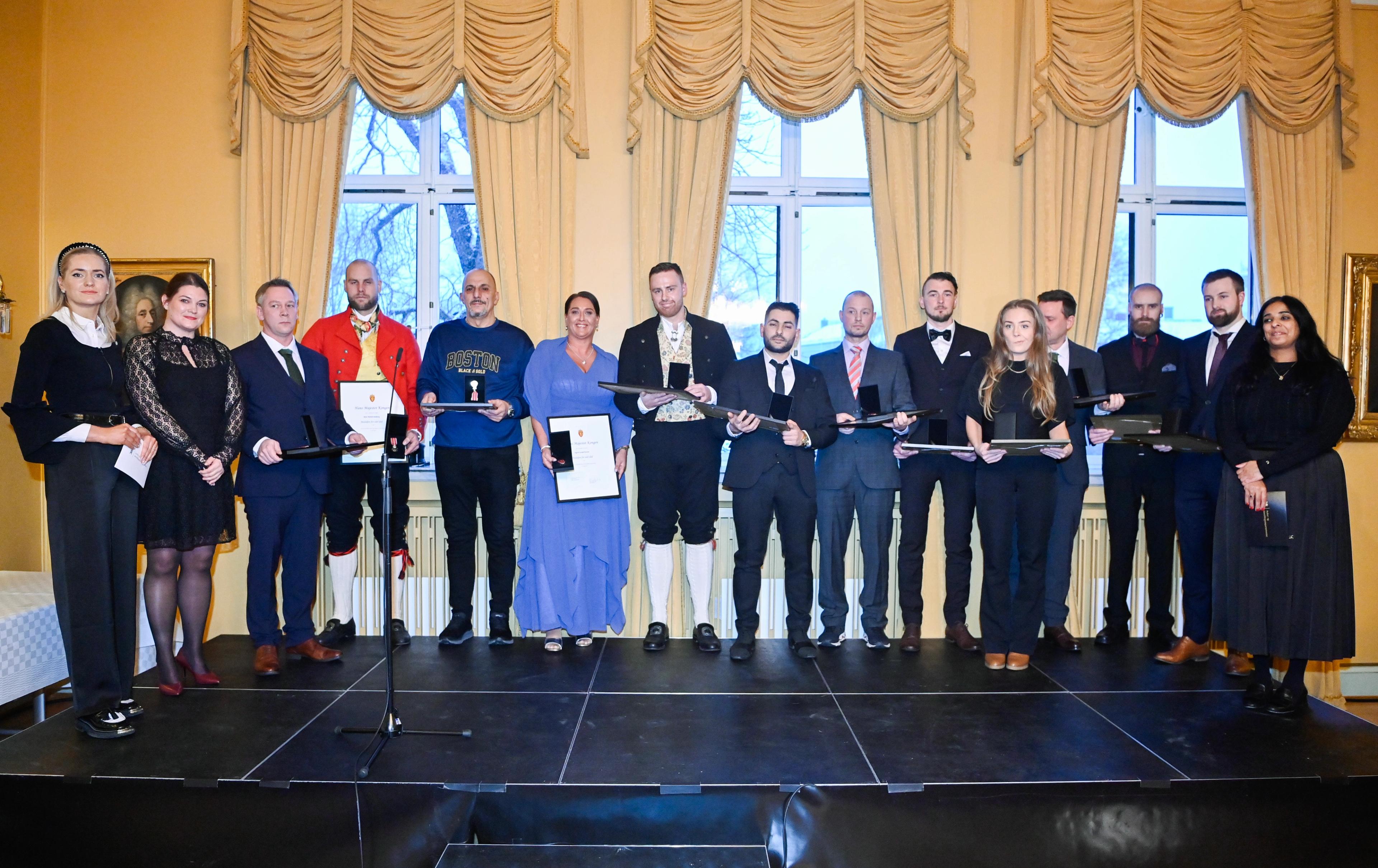 De 12 som fikk medaljen for edel dåd poserer for fotografene sammen med de tre statsrådene som delte ut medaljene.