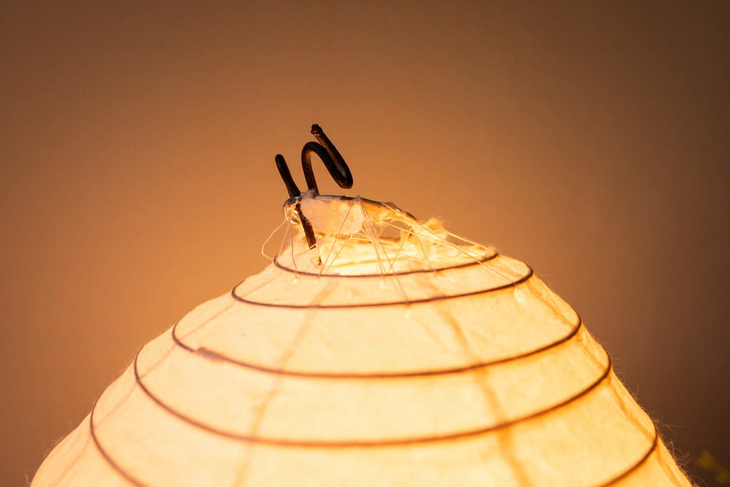 Detail of the kintsugi repair on the paper shade, a dark line stitched across the glow.