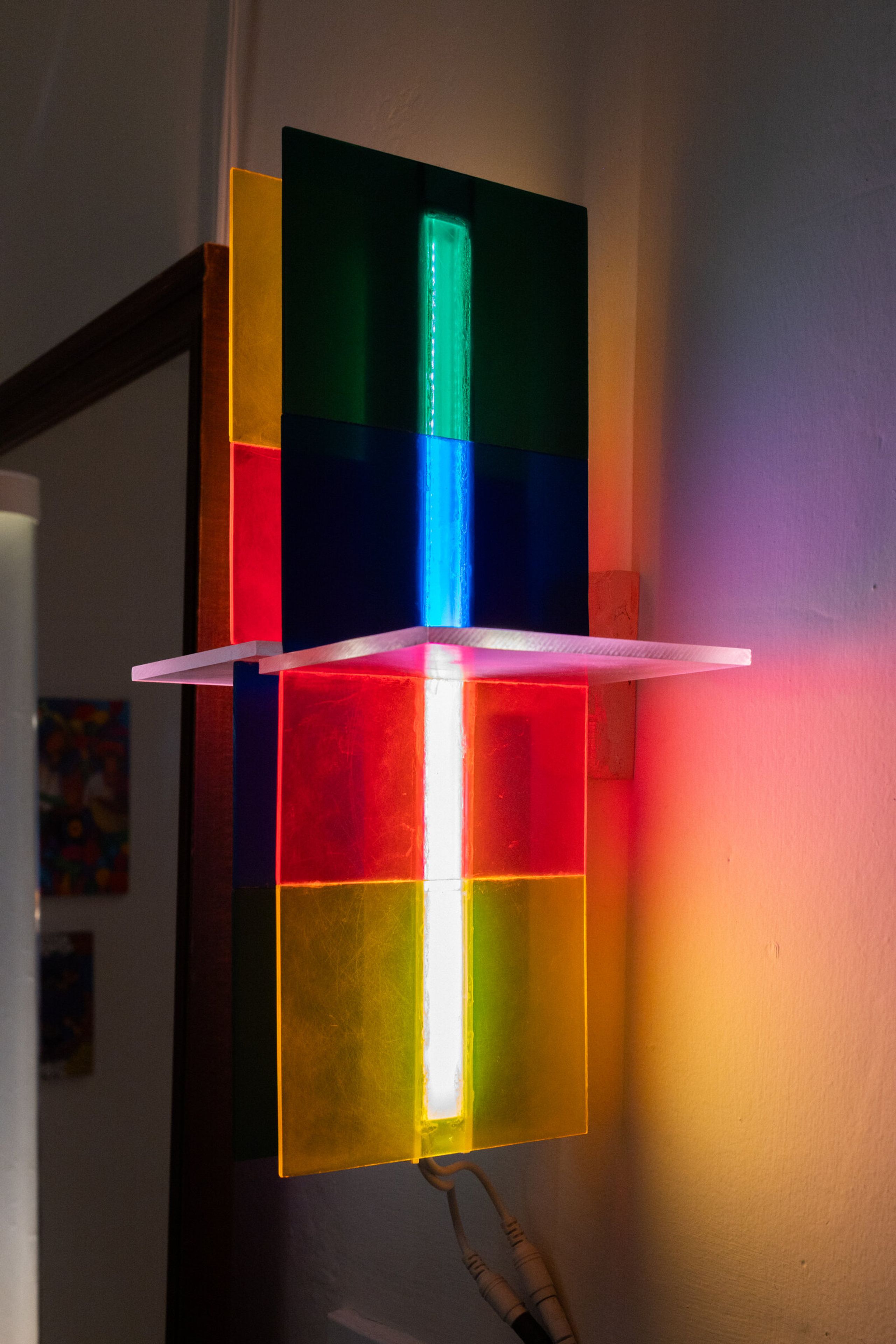 Three-quarter view of irreversible: panels of green, blue, red, and yellow stacked through the vertical column, with the central LED streak visible