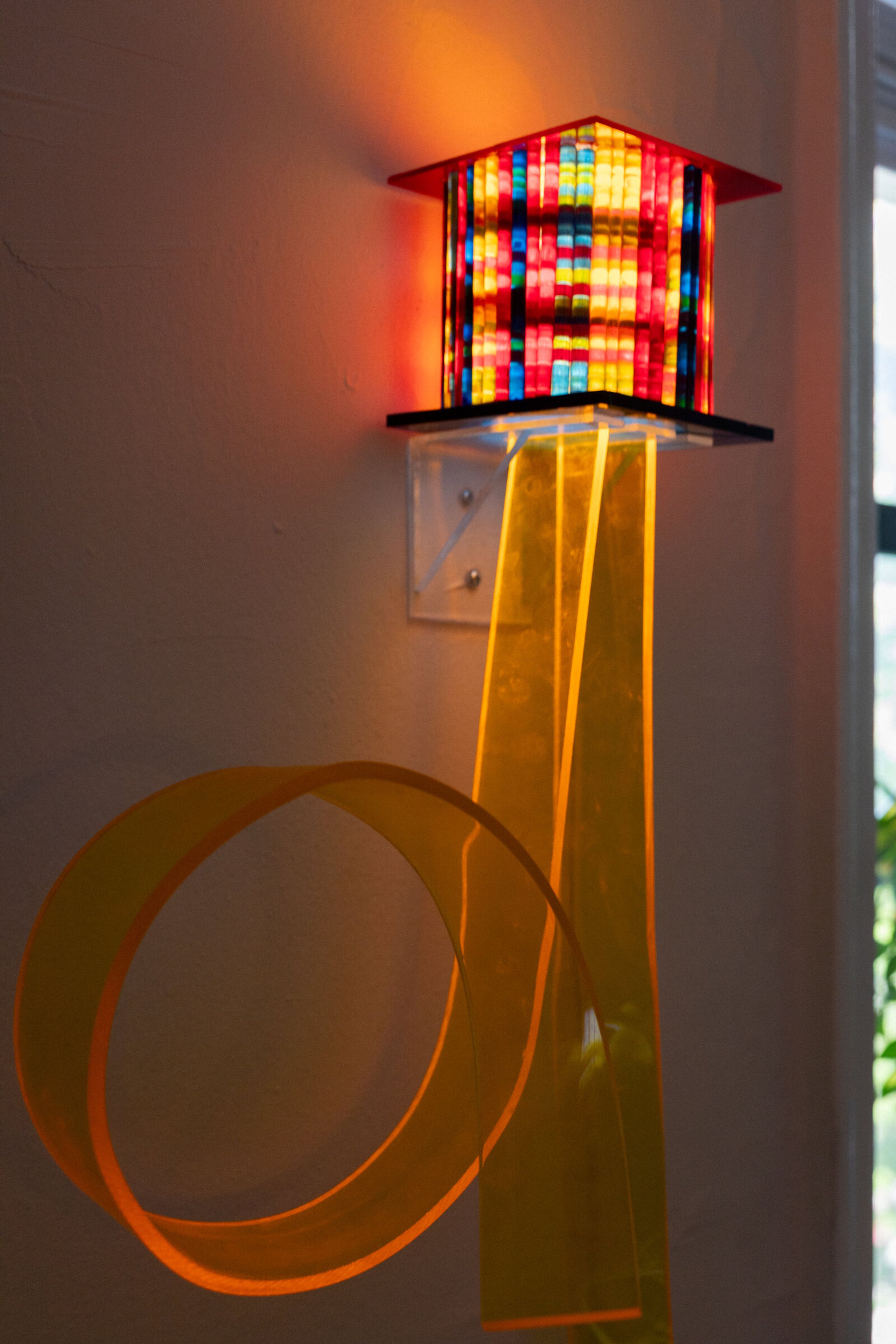 Lower angled view of i've been thinking about flowers: the box visible above, two long orange ribbons descending with a large open loop in the foreground