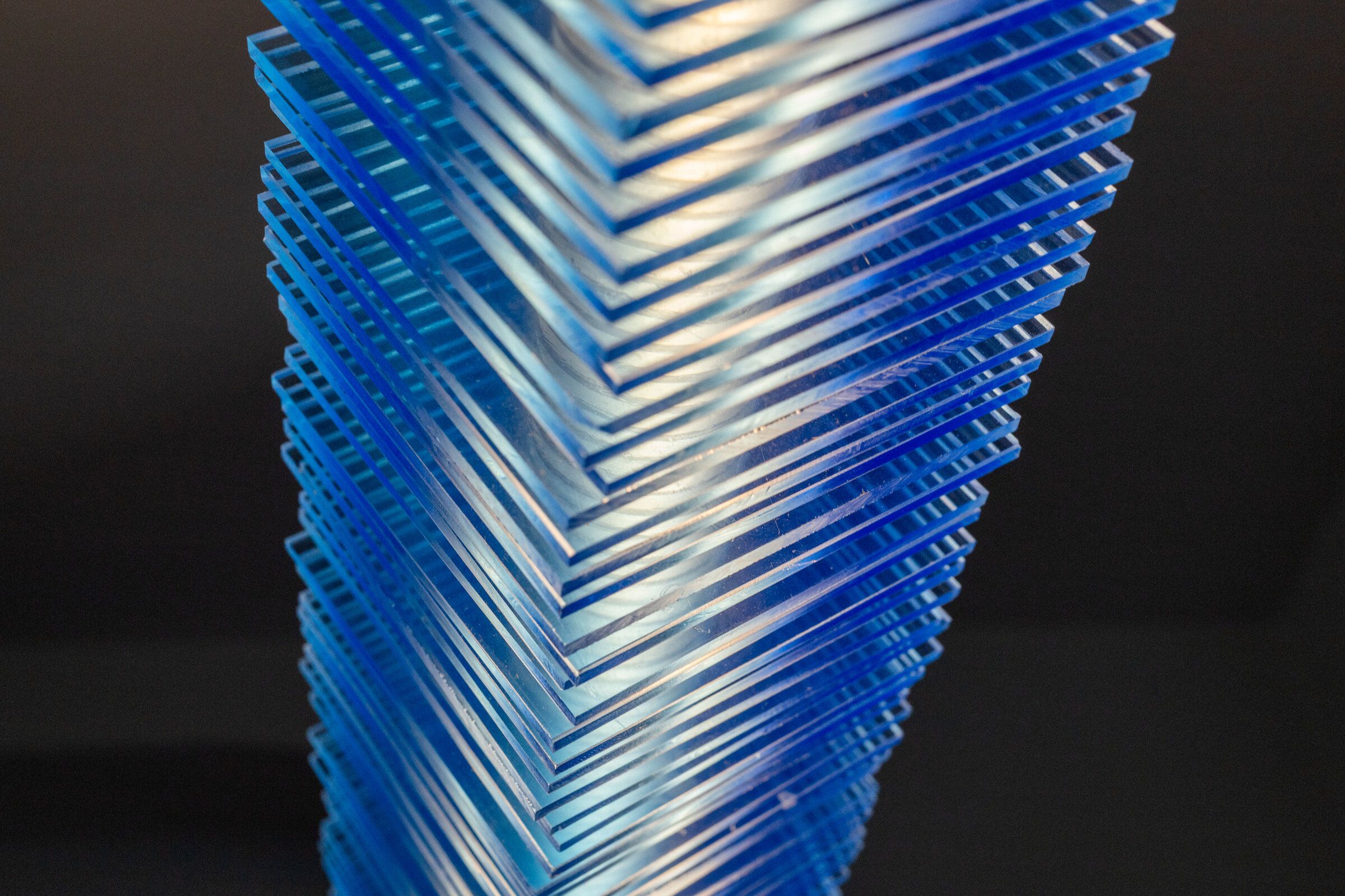 Close-up of the cut end of radiator I: stacked blue acrylic plates visible as parallel horizontal lines, hand-cut edges showing slight irregularities