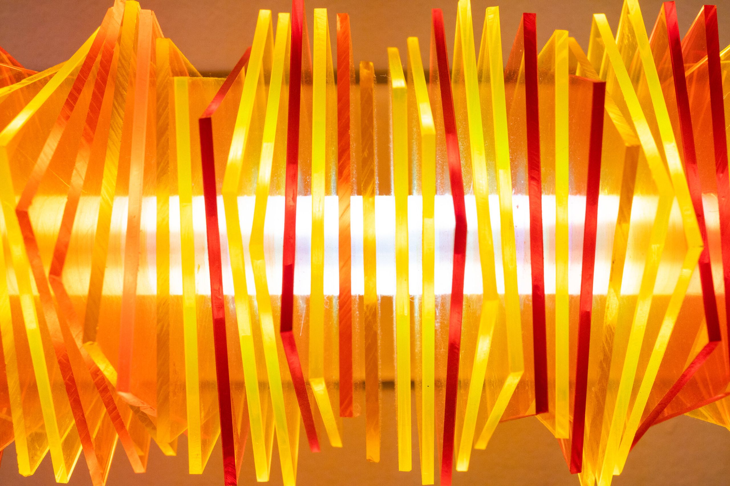 Head-on view of radiator II: the rotated plates resolve into a clean horizontal arrangement, the bright filament tube visible at the center, color stacked symmetrically above and below