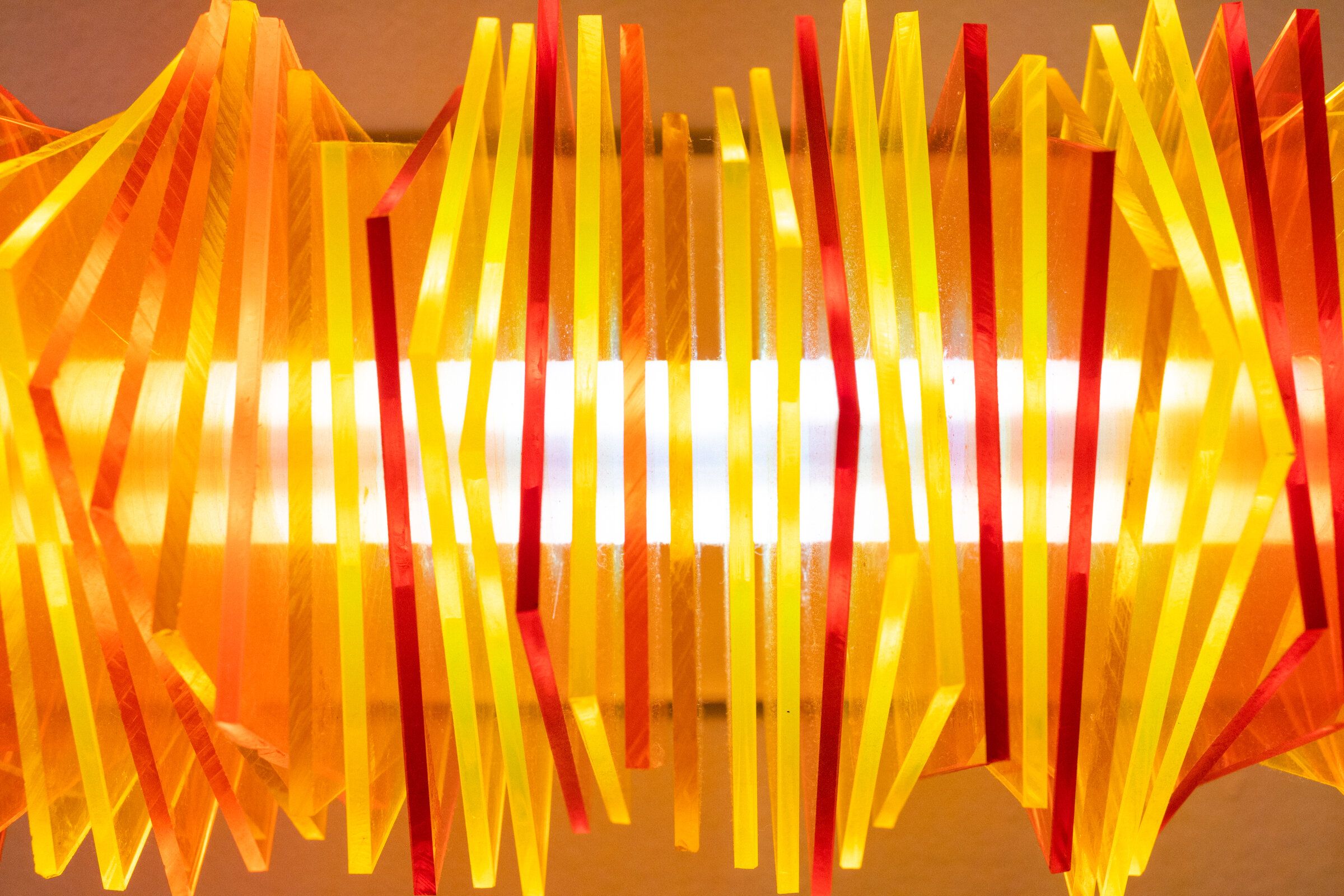 Head-on view of radiator II: the rotated plates resolve into a clean horizontal arrangement, the bright filament tube visible at the center, color stacked symmetrically above and below