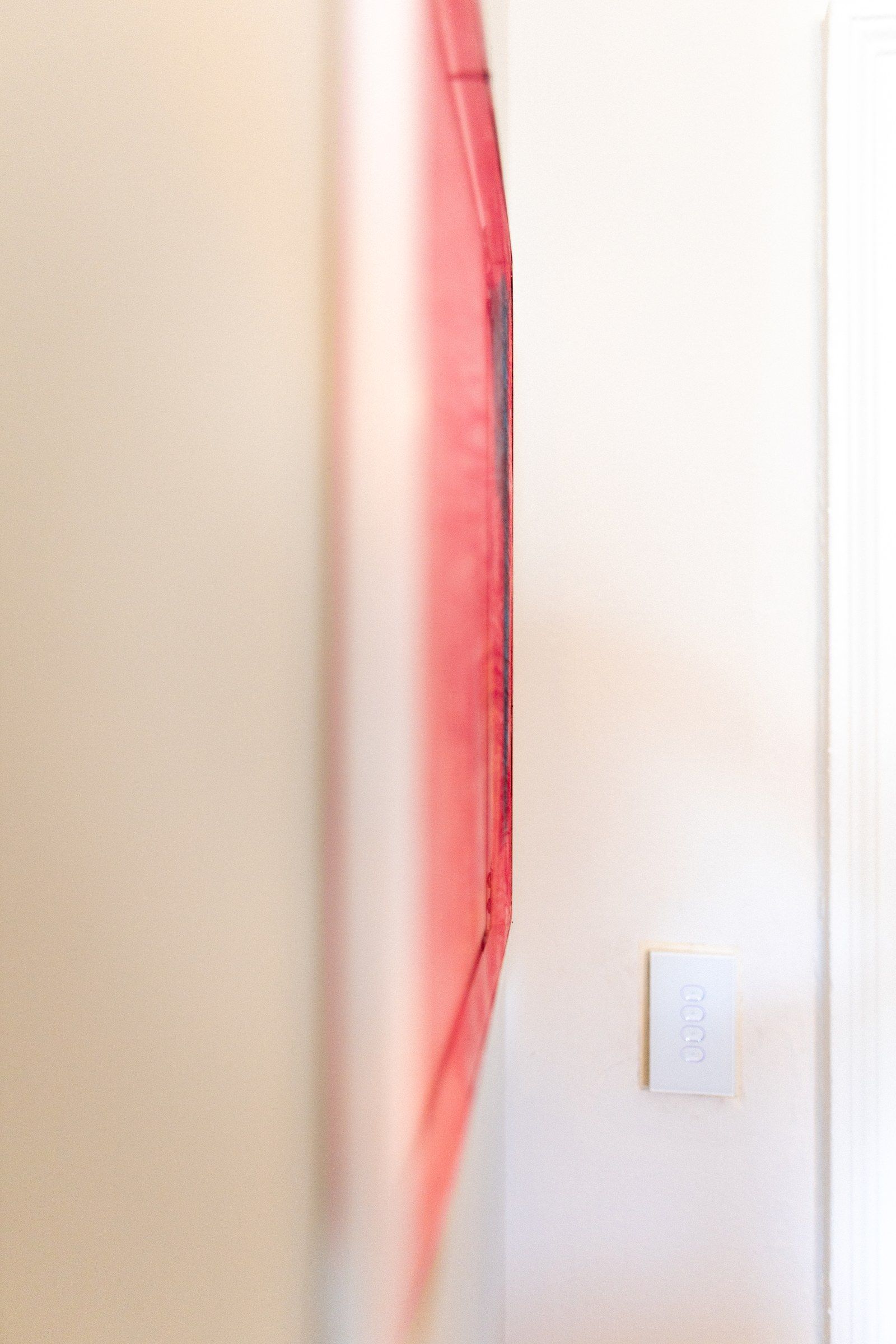 Close view of the sheer fabric, its weave and pink gradient within the frame.