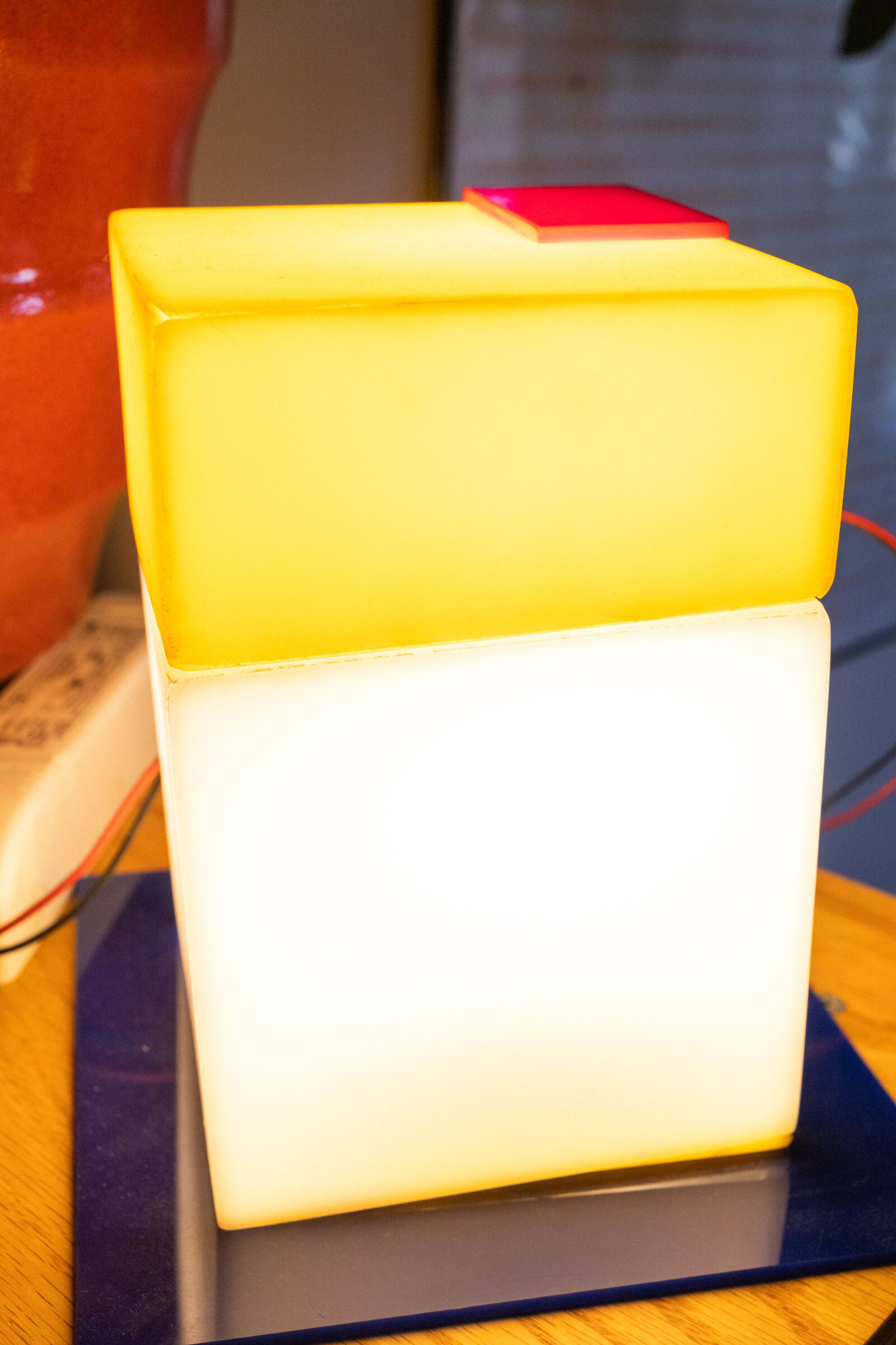 Parts and all head-on: the yellow cap above the bright white cube, the blue plate at the base, the small red square offset at the top