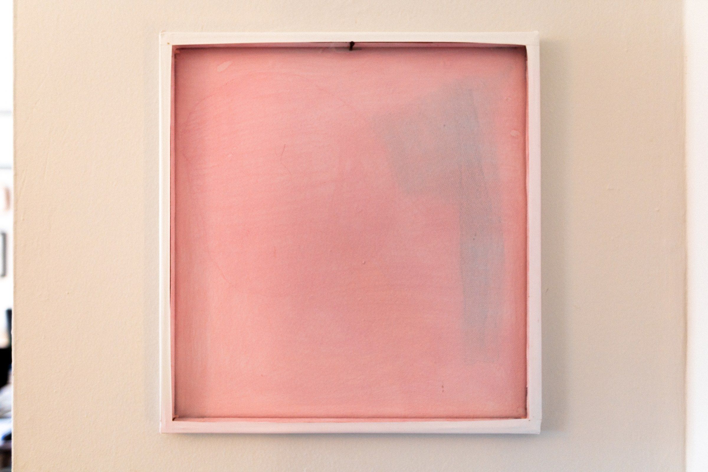 A square panel of sheer pink fabric stretched flat in a white frame on a wall, a soft red-to-pink wash within.