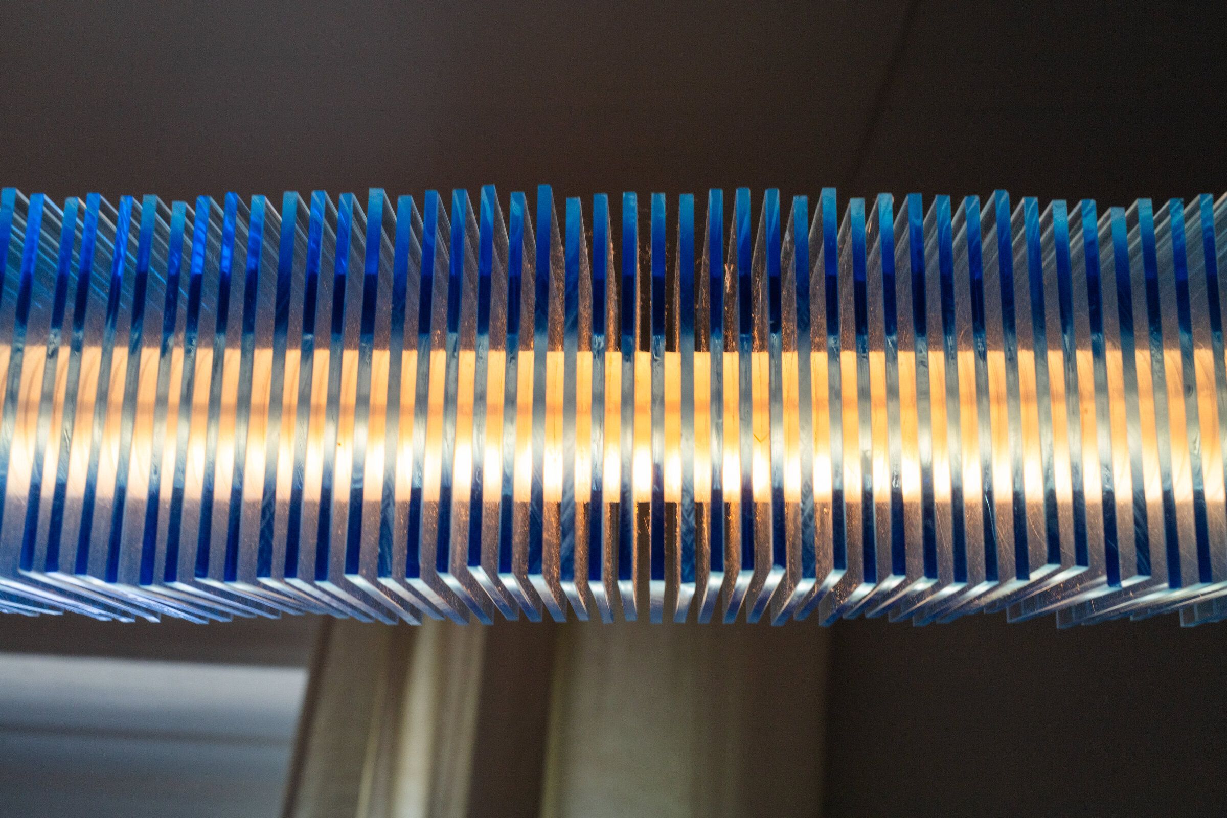 Close-up of radiator I from the side: the plates resolve as vertical blue fins, warm light glowing horizontally between them