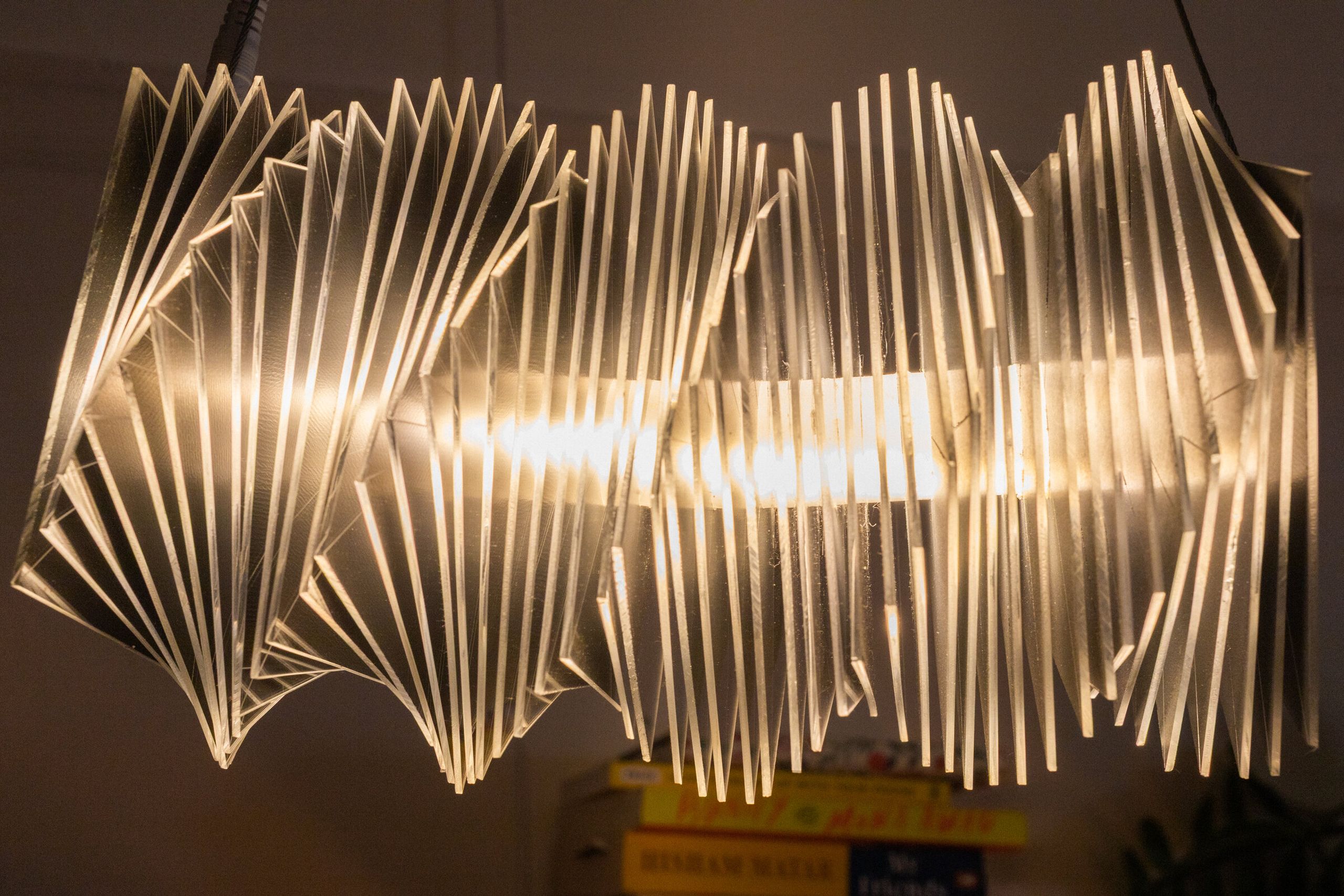 Close side view of radiator III: mirrored acrylic plates resolved as vertical fins, warm light glowing horizontally between them