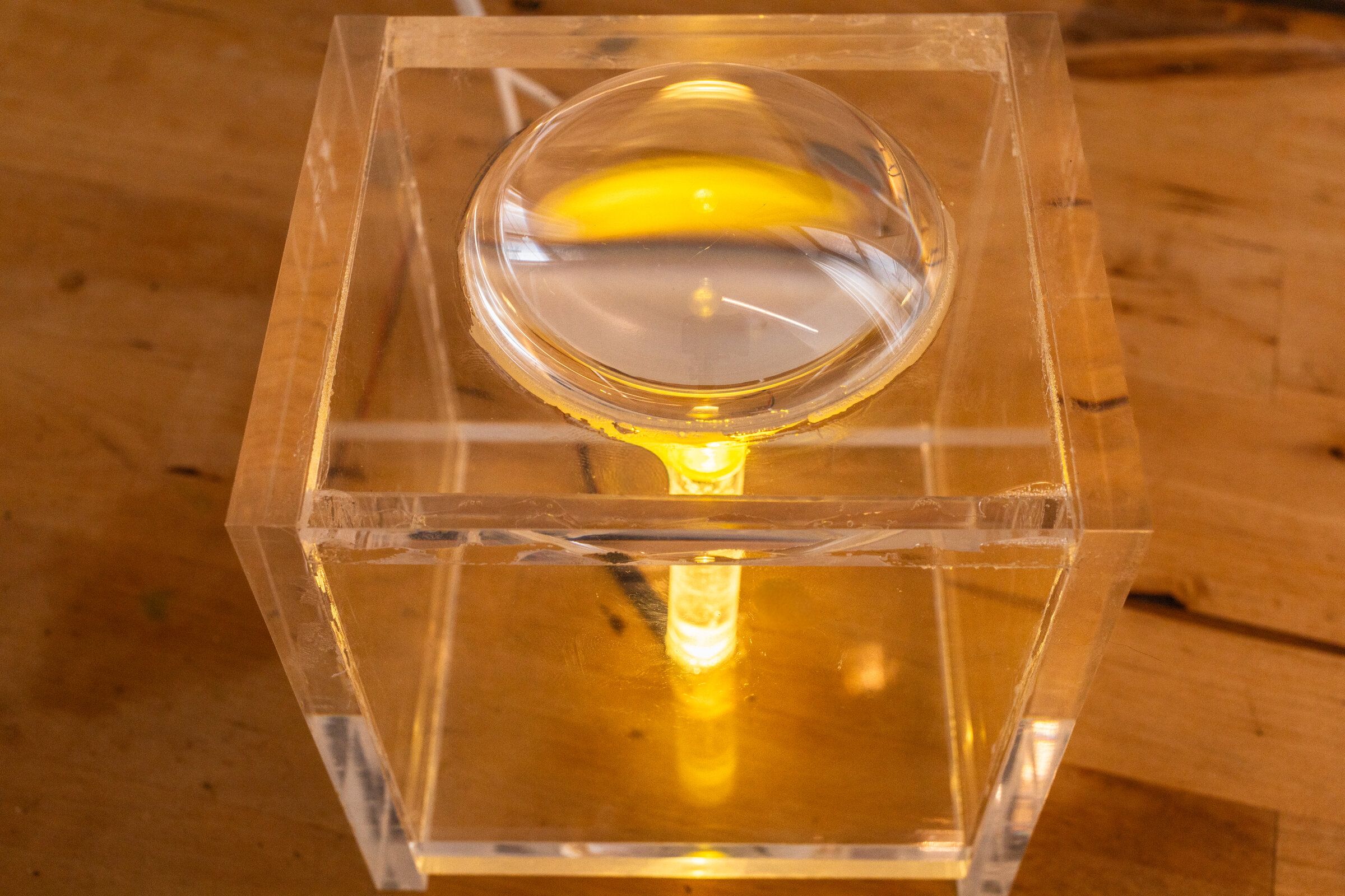 Top-down view of internal artifact through the lens: a yellow scroll of text inside the cube magnified by the dome lens
