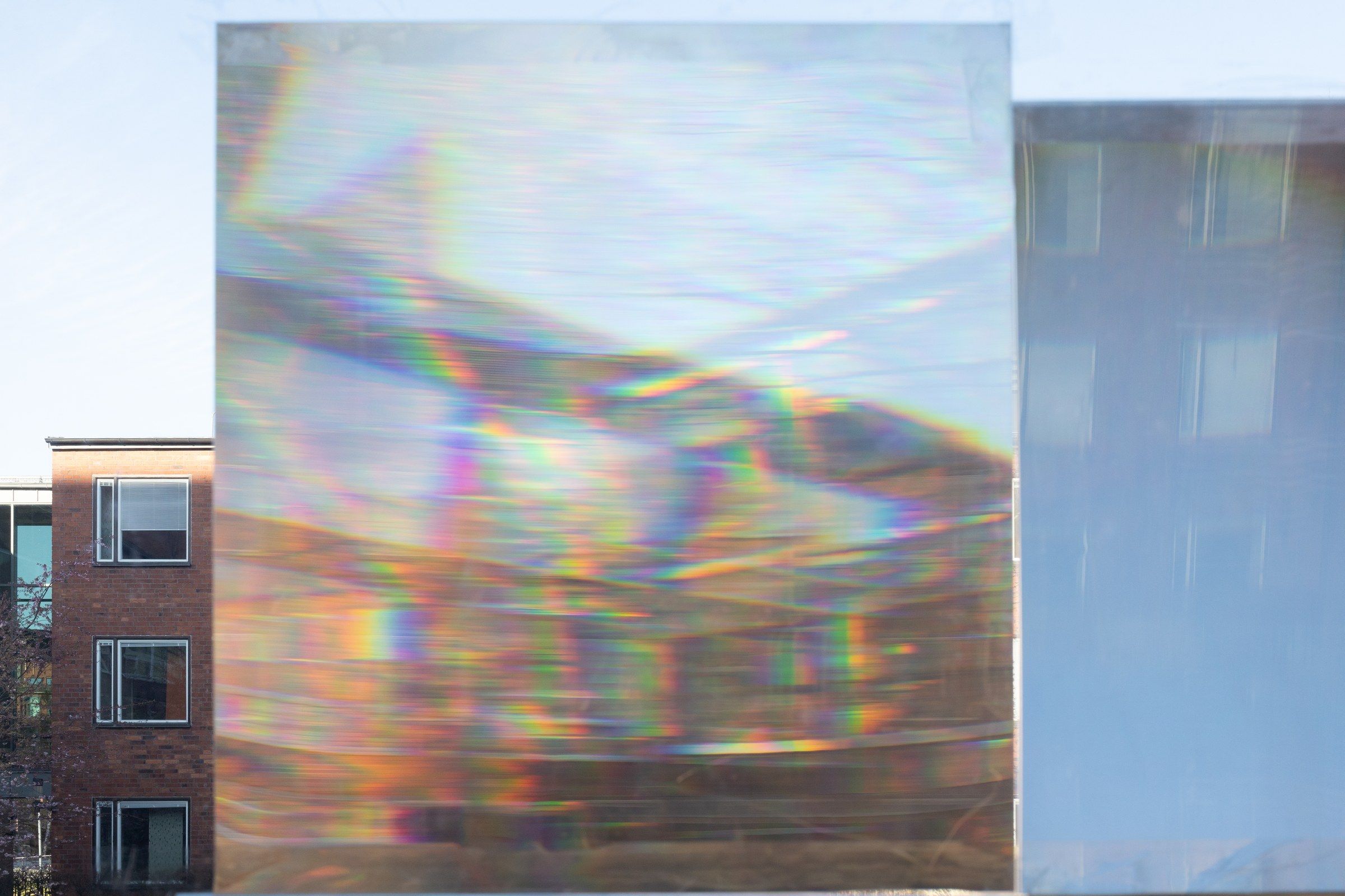 Refracted light scattered across a pale wall beside a window, faint spectral streaks.