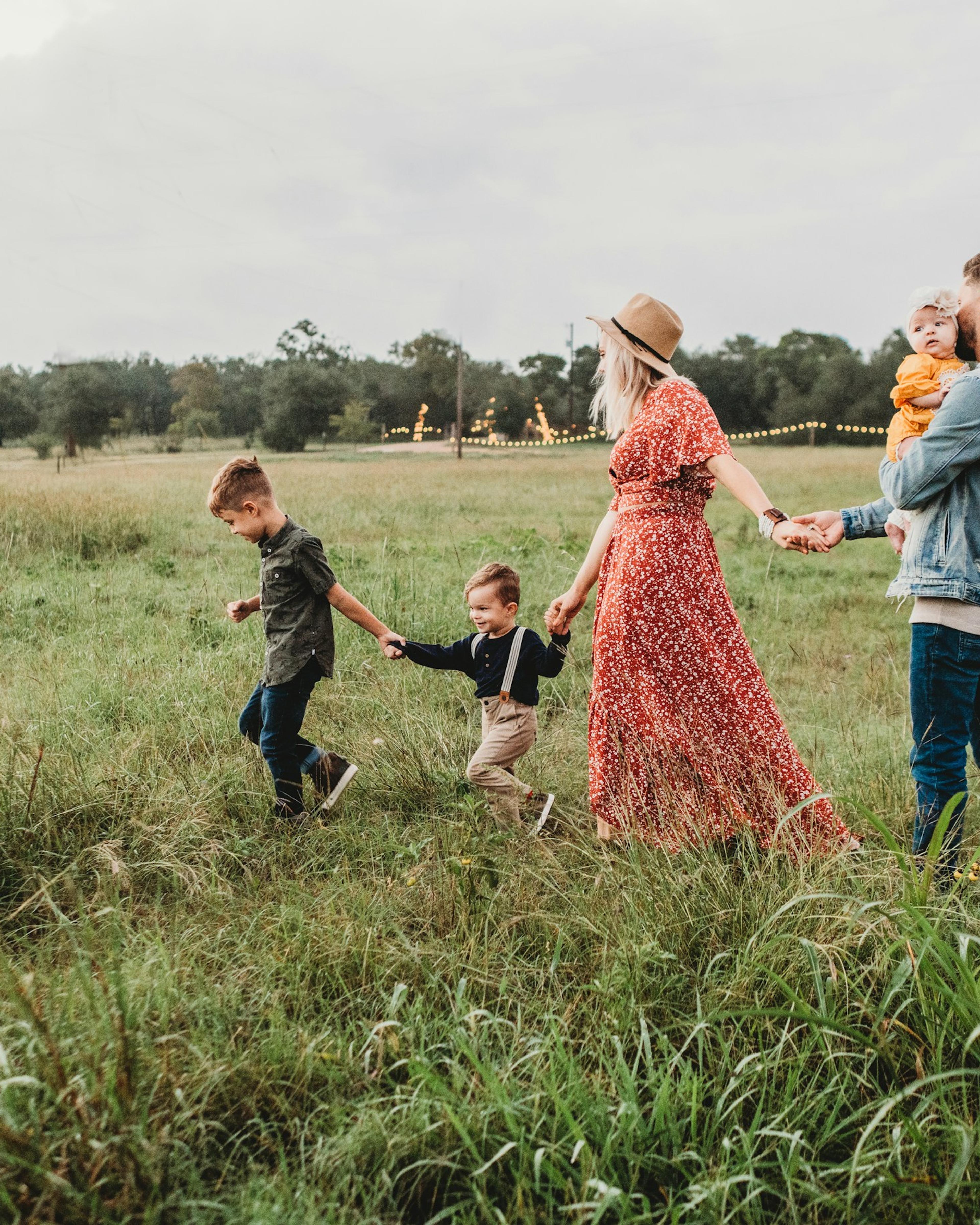 Familie läuft Hand in Hand über eine Wiese