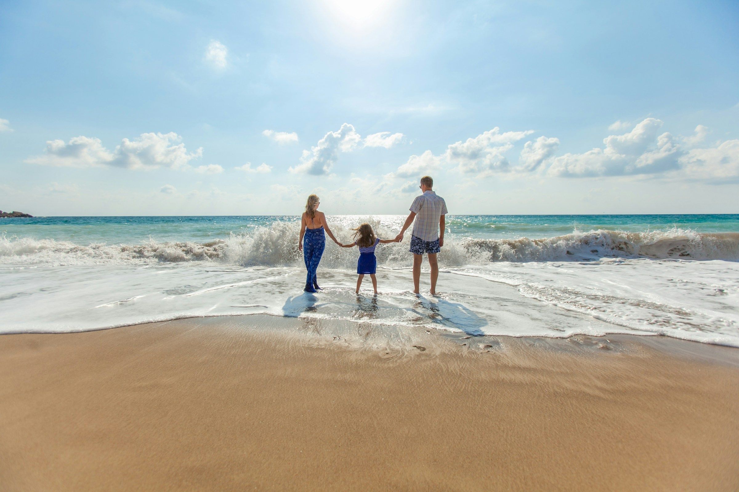 Familie geht Hand in Hand am Strand zum Meer