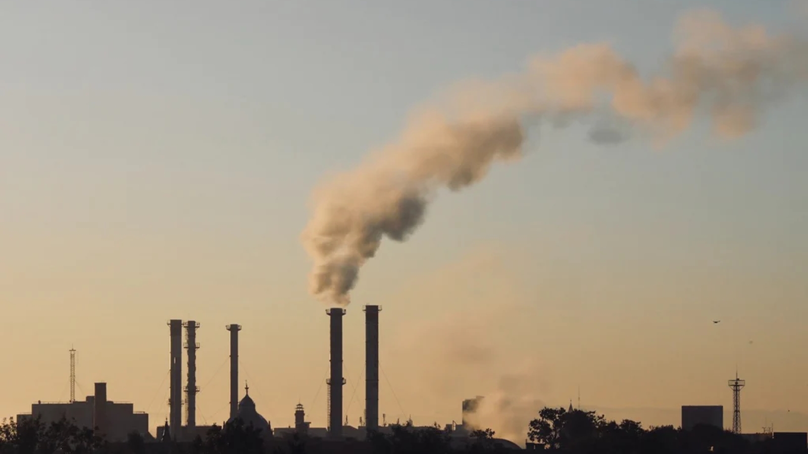 several smoke stacks silhouetted against an evening sky