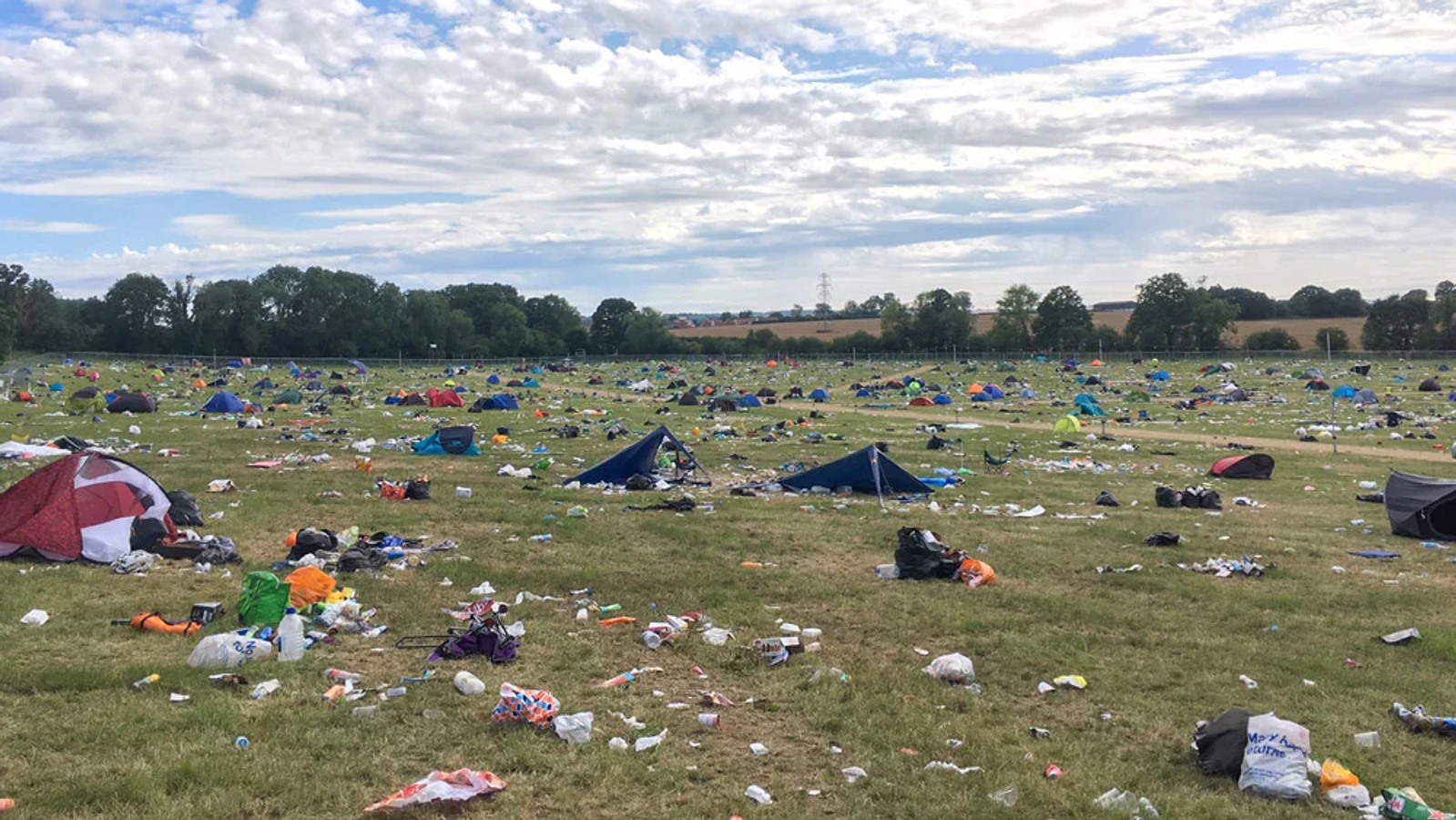 A field at the end of a festival, covered in plastic waste and discarded tents