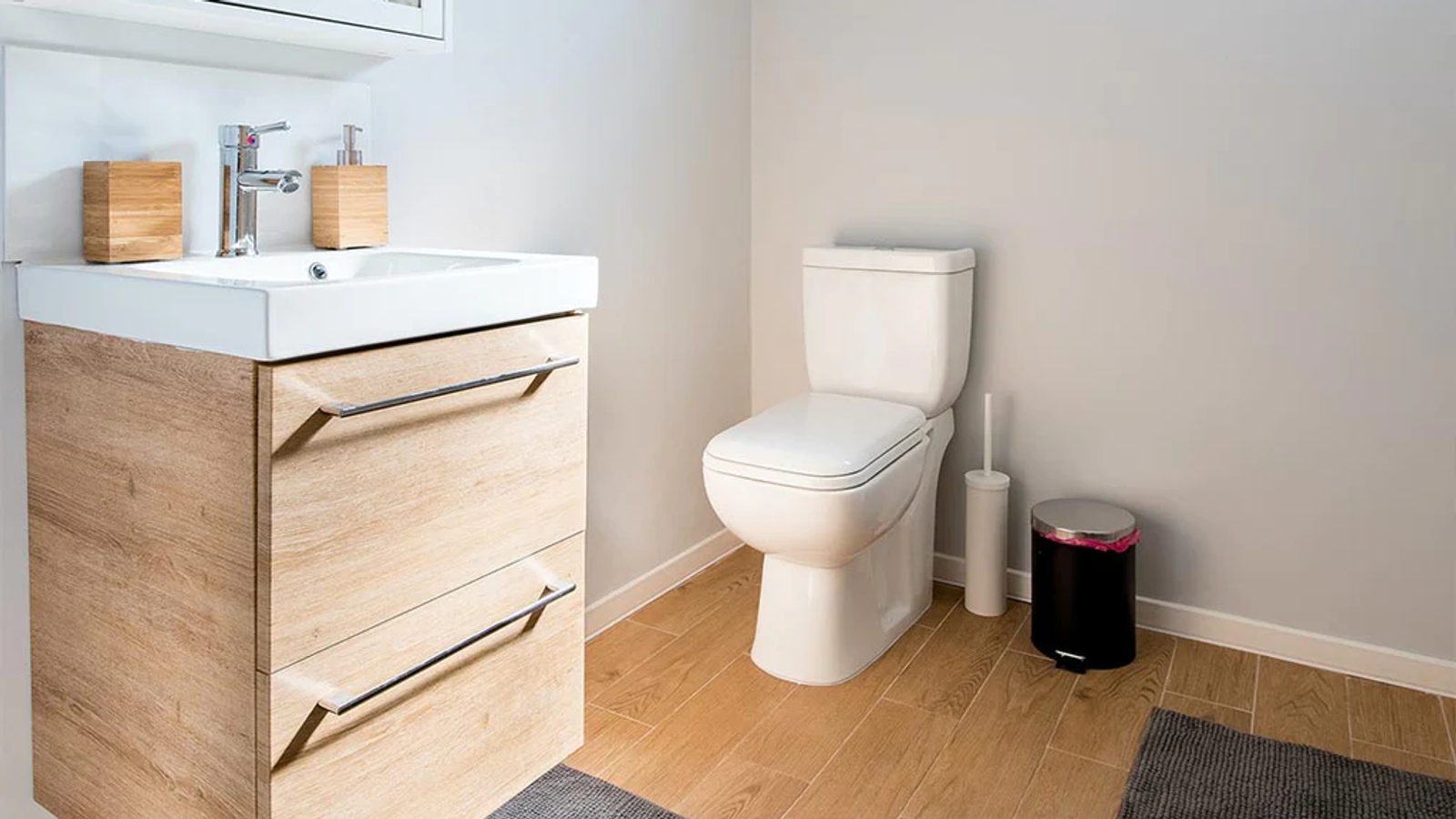 A bathroom with wooden drawers and white sink and a white toilet