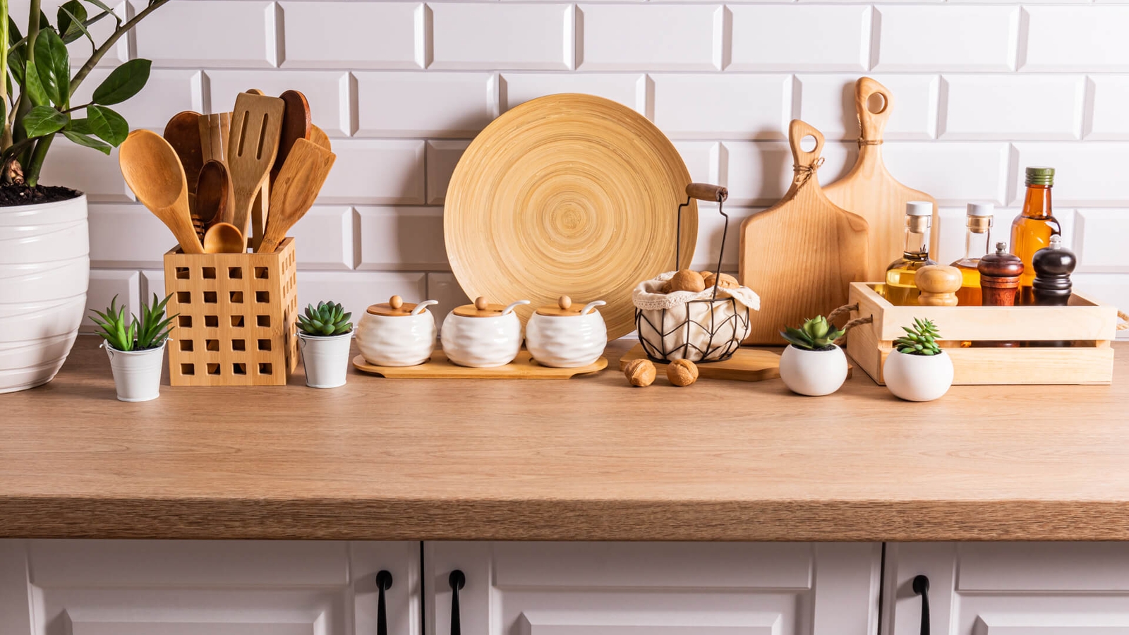 A wooden kitchen countertop with kitchen utensils, chopping boards and oils