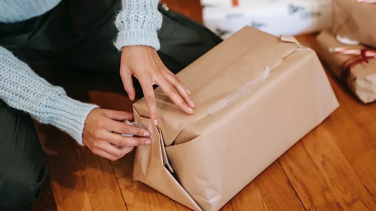 someone wrapping a present with brown paper