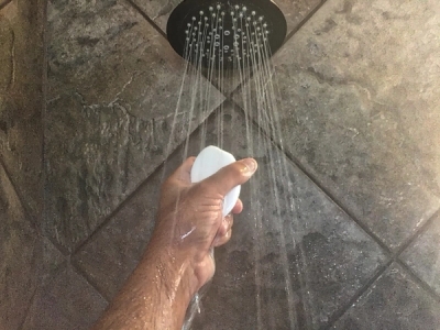 hand holding a soap bar up to a shower head