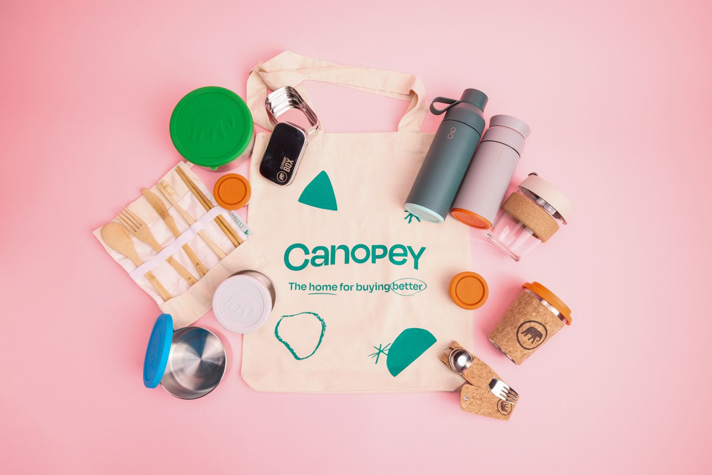 A bunch of sustainable products, including a green and pink water bottle from Ocean Bottle, lunch boxes and reusable water cups from Elephant box put on top of a Canopey tote bag.