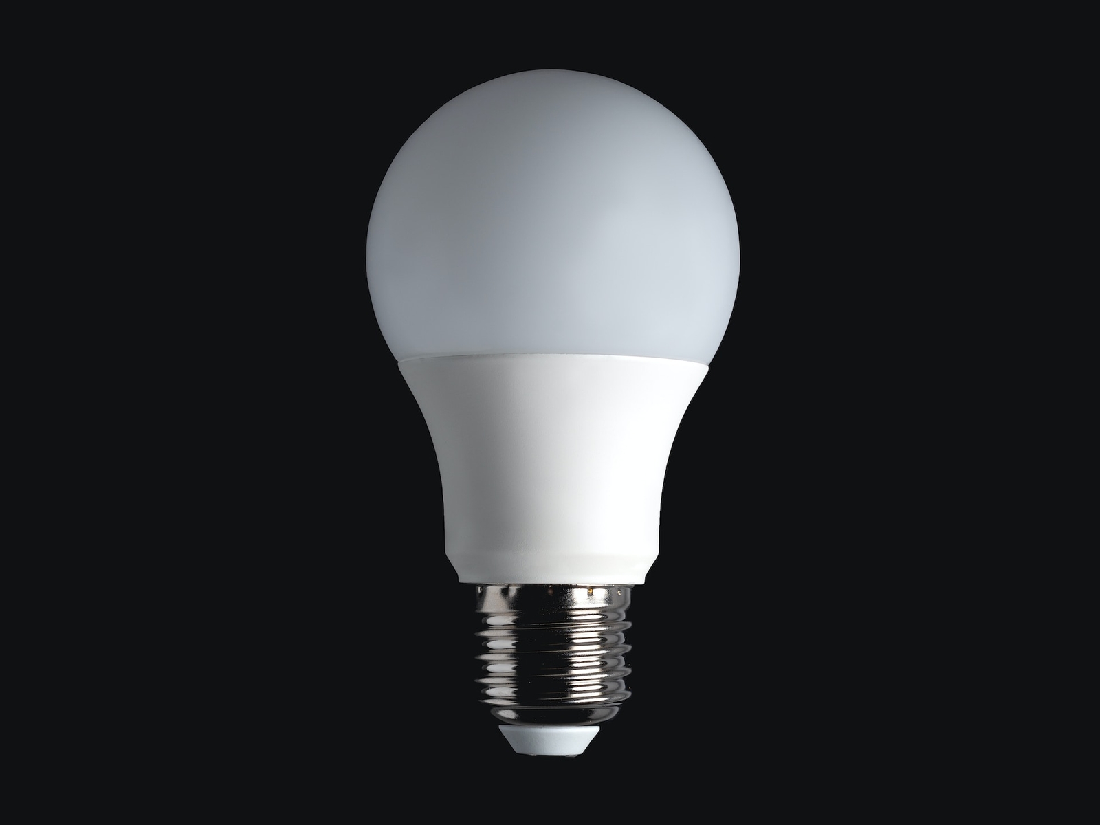 A single LED light bulb illuminated, centered against a pure black background.