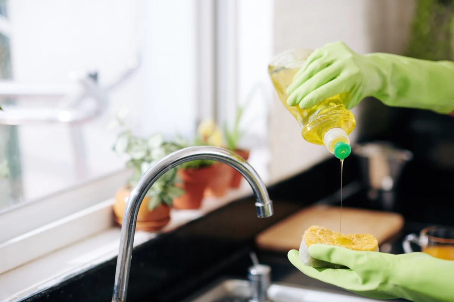 Pouring washing up liquid on a cleaning sponge