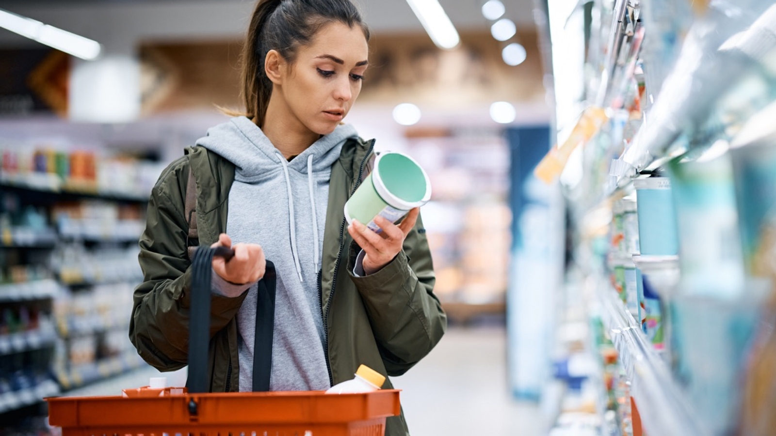 Woman checking label on carton of food at supermarket