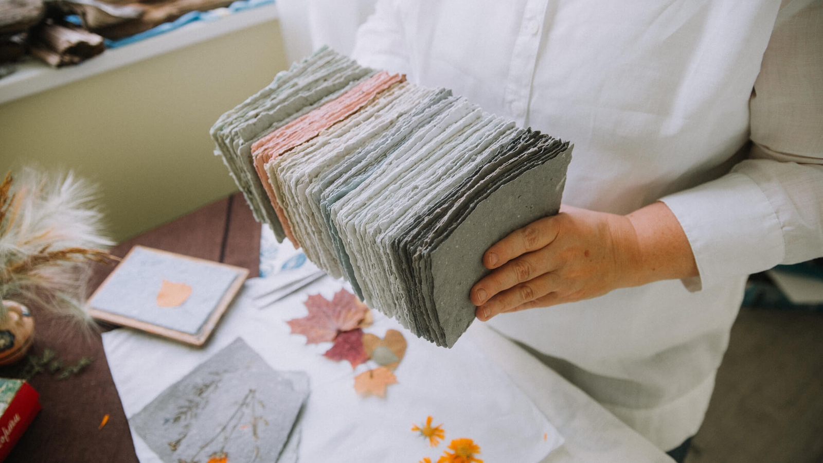 Someone holding together a stack of pieces of craft paper