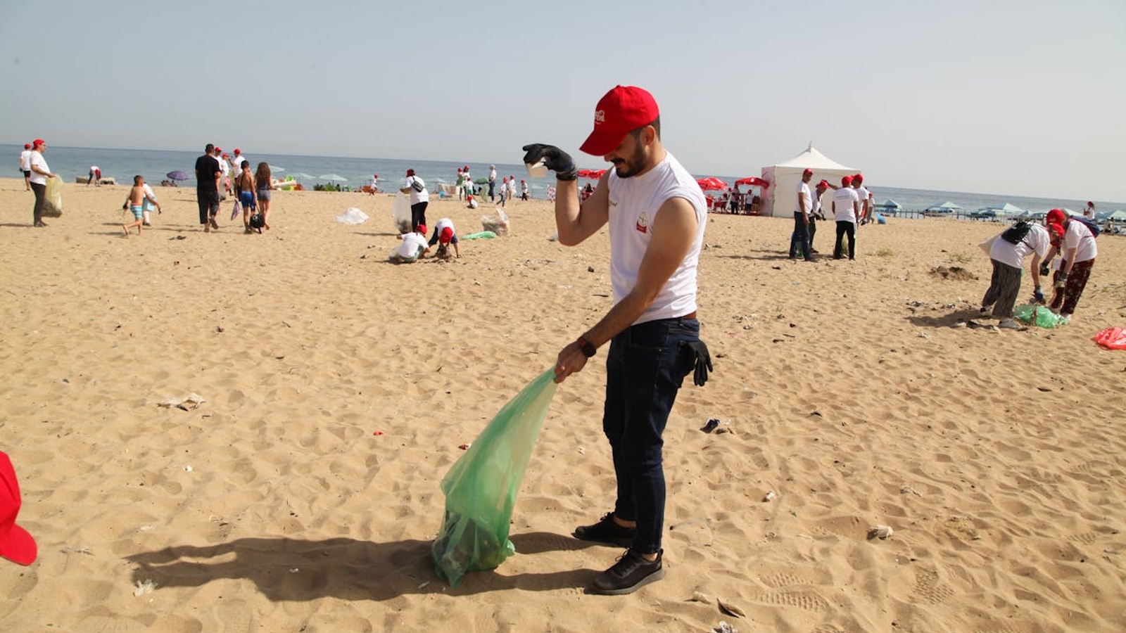 A man on a beach cleaning up rubbish into a plastic bag