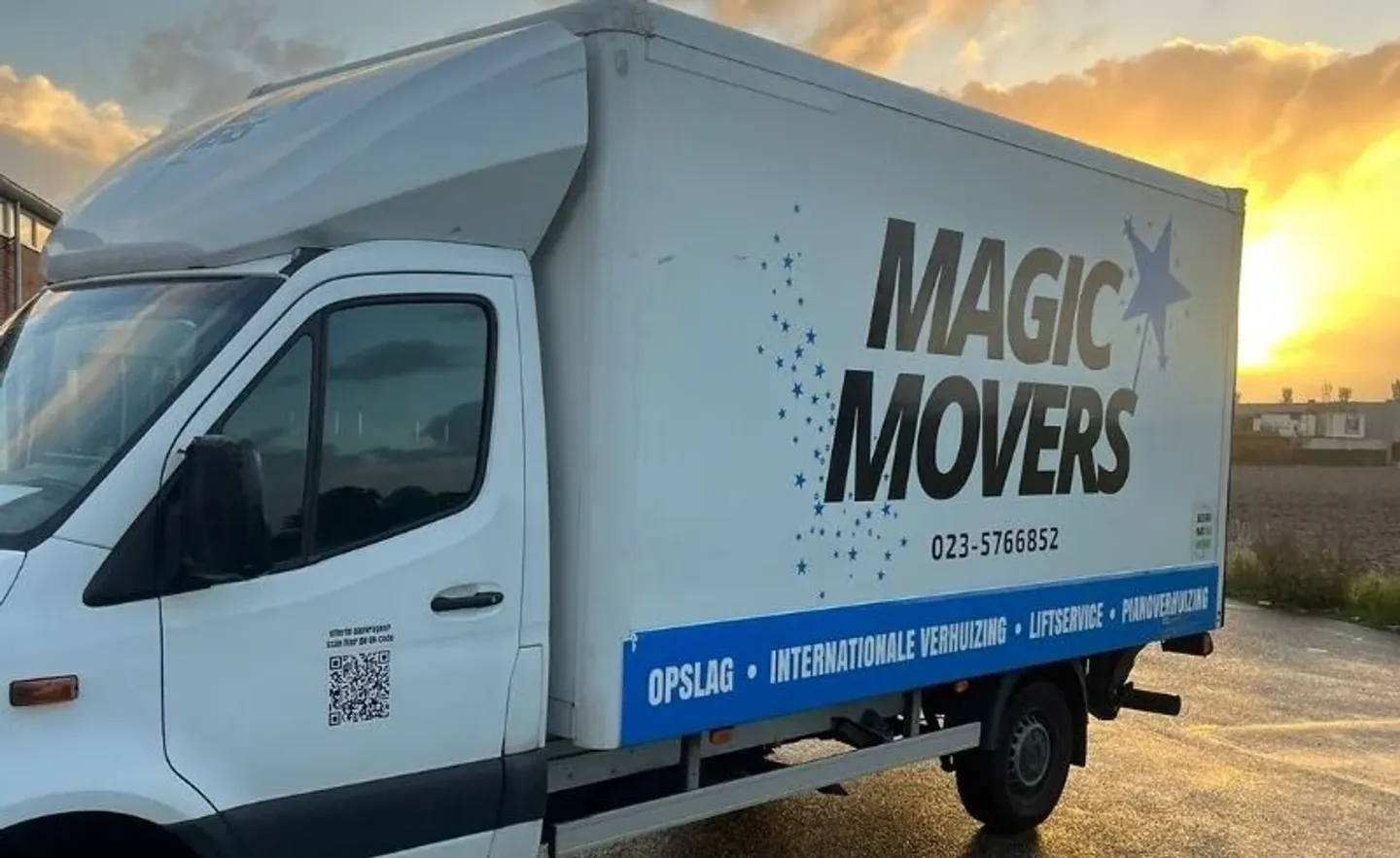 Magic Movers moving truck with logo and contact details on the side, photographed at sunset