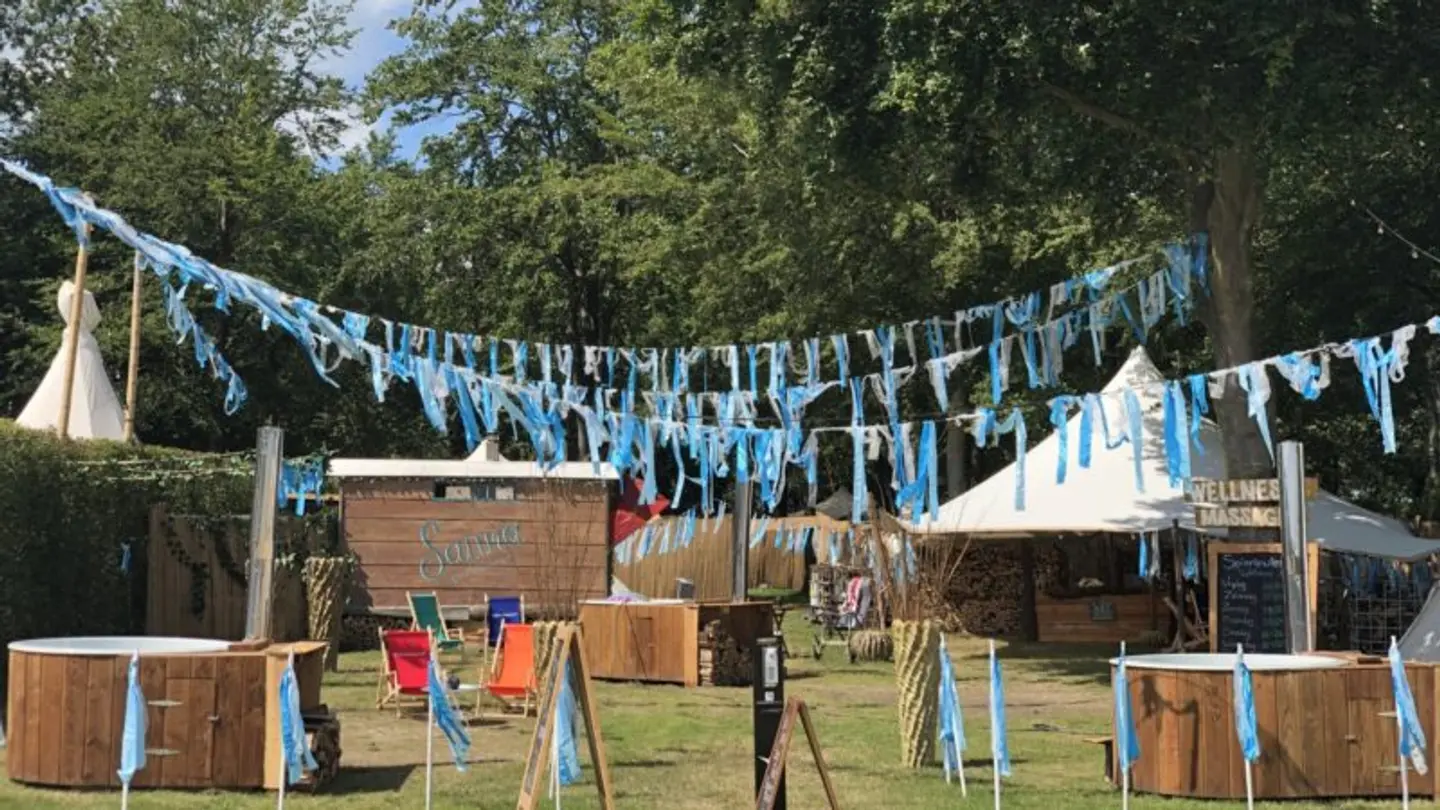 Spieriewierie wellness setup at a festival with blue ribbons, sauna huts and hot tubs