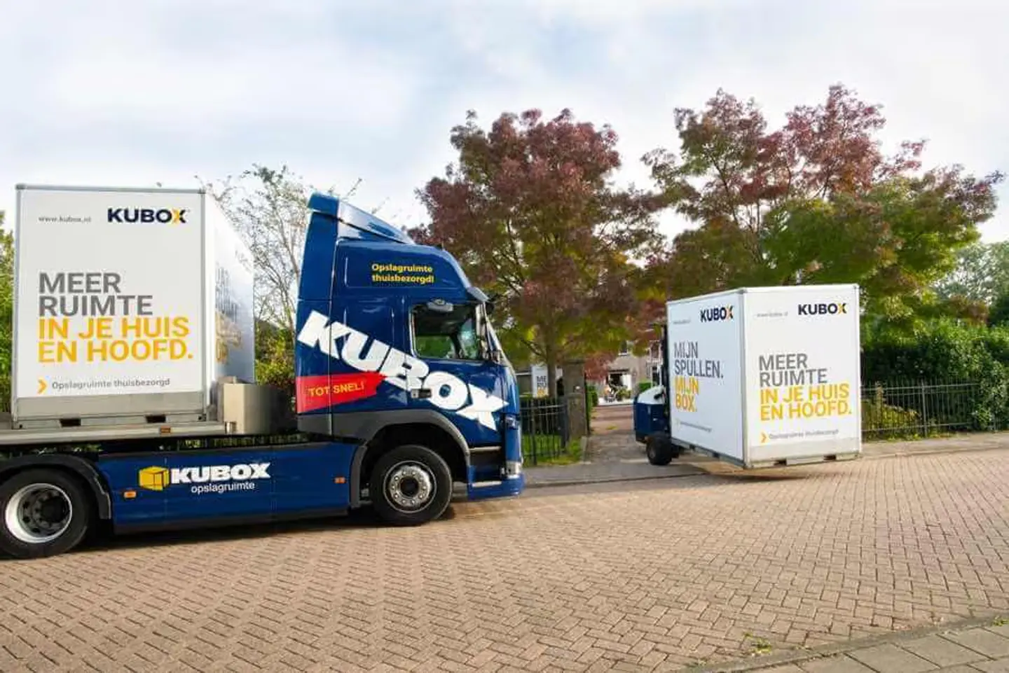 Kubox-trailer met meerdere mobiele opslagboxen achterop, onderweg om aan huis afgeleverd te worden