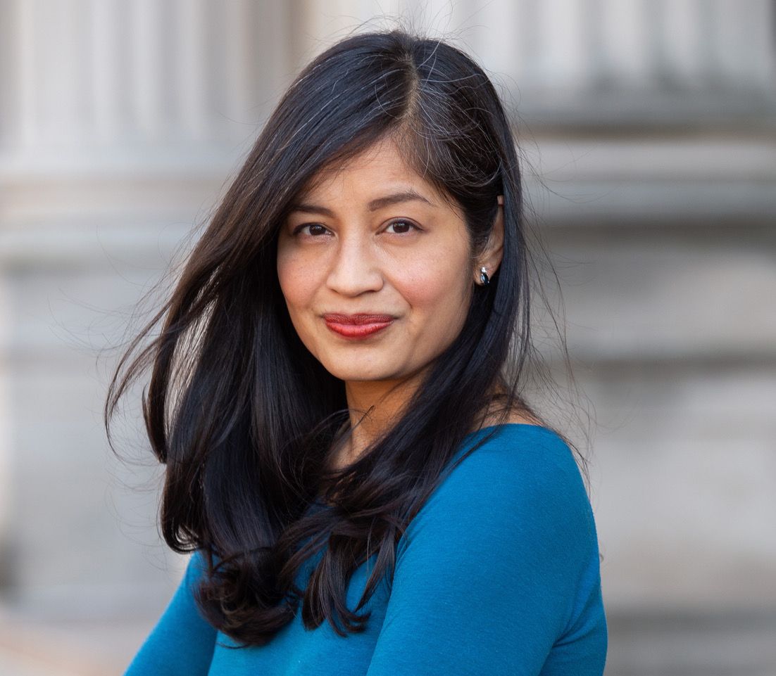 Denis Cruz headshot, she wears a blue shirt