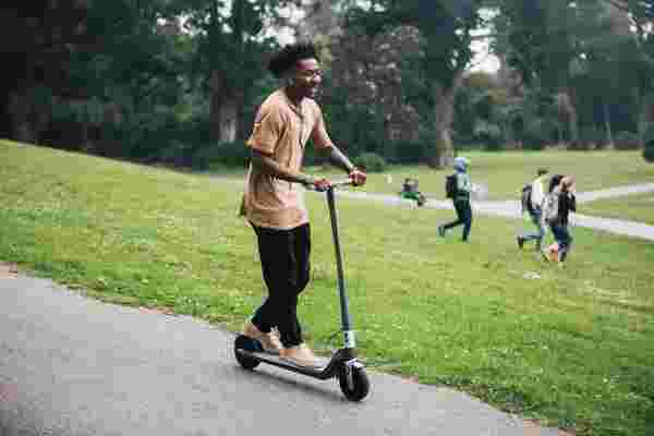 Young man riding electric scooter in park