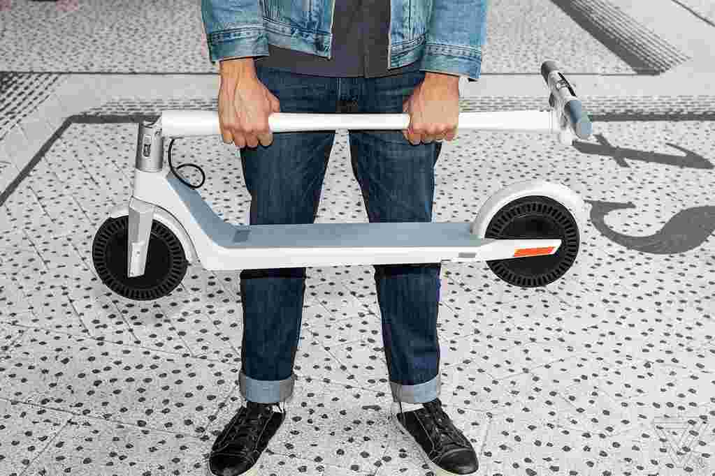 man holding folded unagi electric scooter