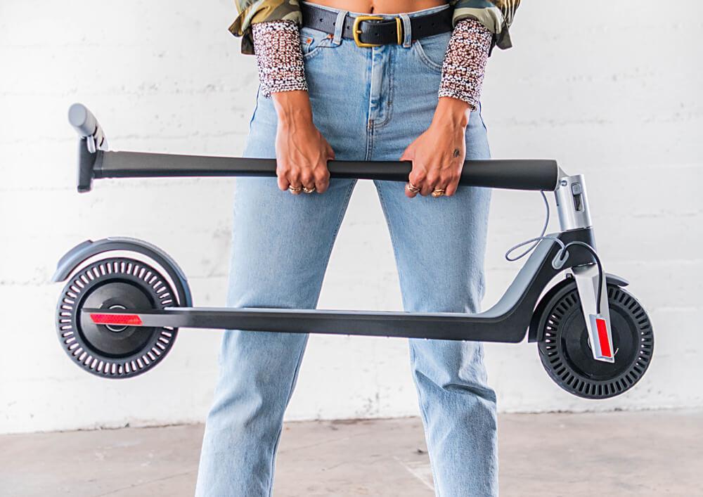 Woman holding a folded e-scooter