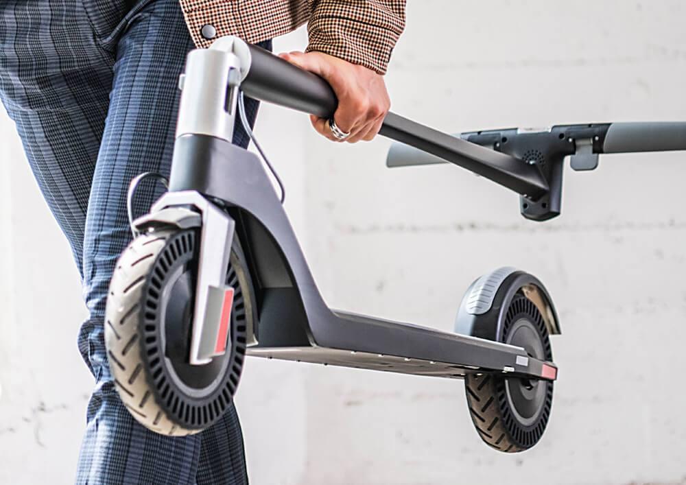 Man holding a folded e-scooter