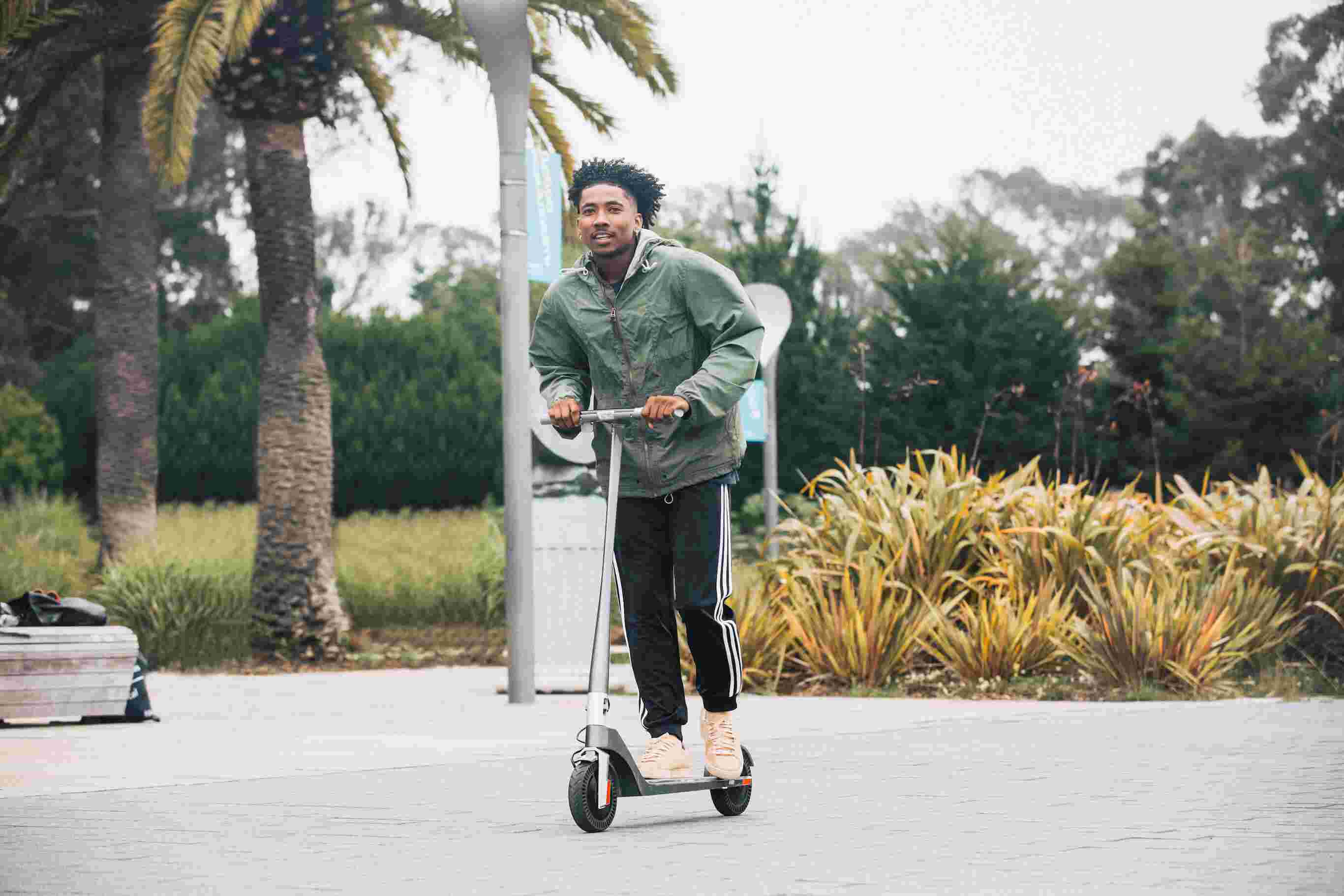 Black Young Male Riding Adult Electric Scooter Outdoors