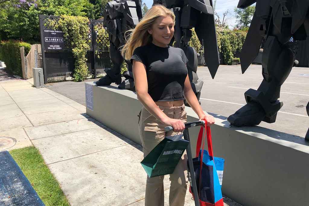 woman riding electric scooter shopping bags