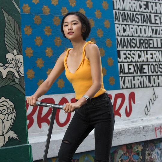 Femme sur trottinette électrique avec fond mural