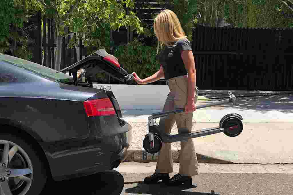 woman putting electric scooter in car