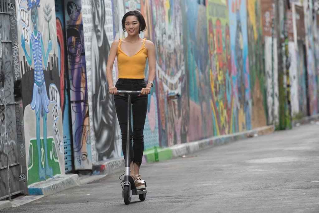 asian woman riding unagi electric scooter graffiti