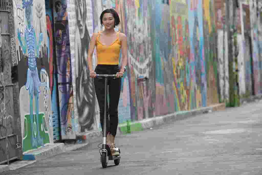 asian woman riding electric scooter graffiti