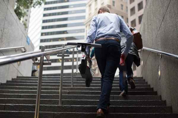 Man walking up stairs carrying electric scooter